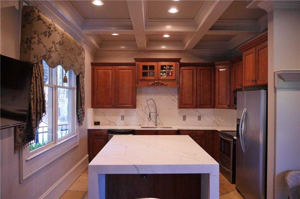 Elegant kitchen with cherry wood cabinets, white quartz island, stainless appliances in Davidson Homes The Seaside B, Woodstock, GA