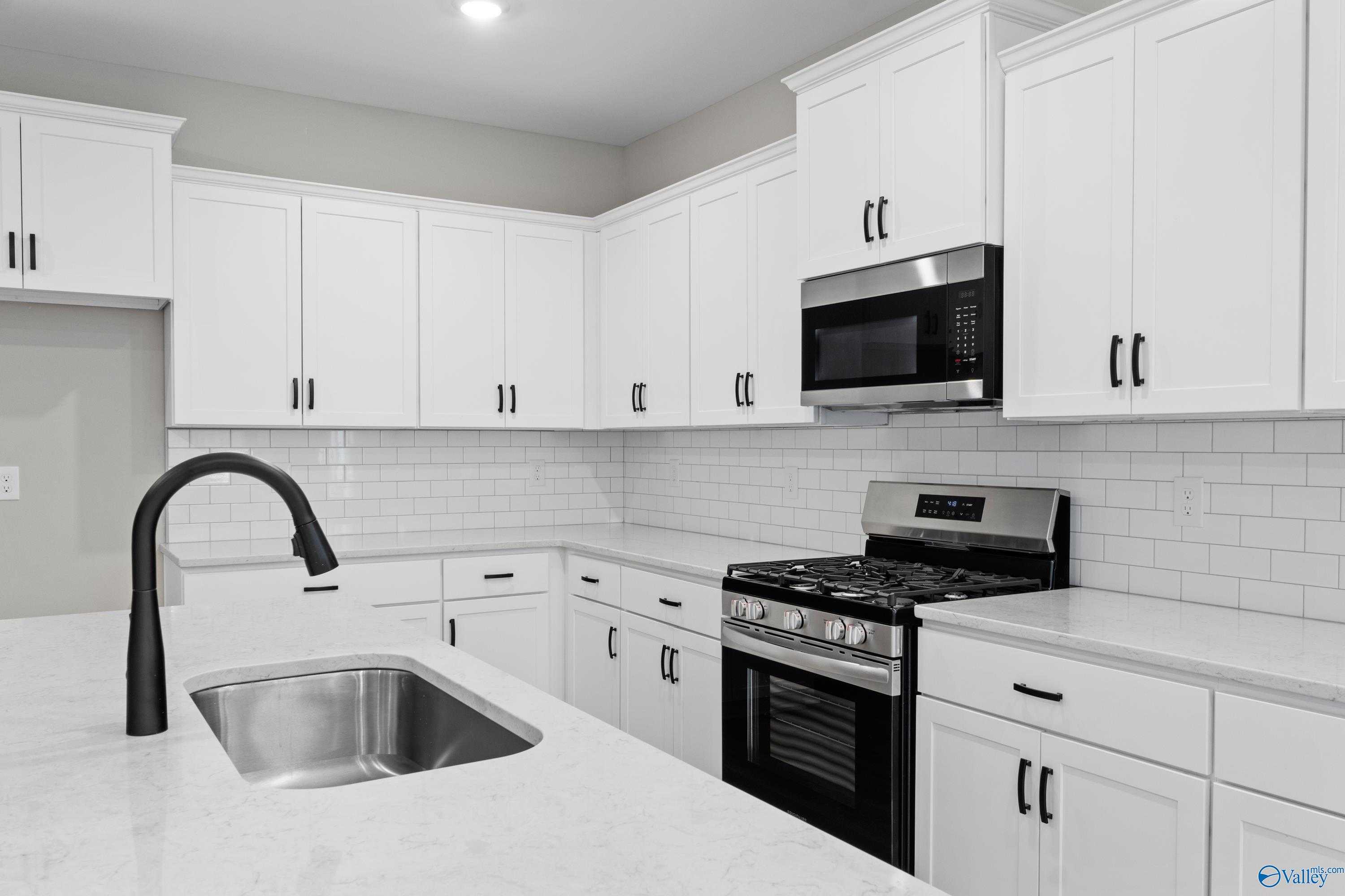 Modern kitchen with white shaker cabinets, quartz countertops, stainless steel appliances in The Nantucket home, Evergreen Mill, Madison, Alabama
