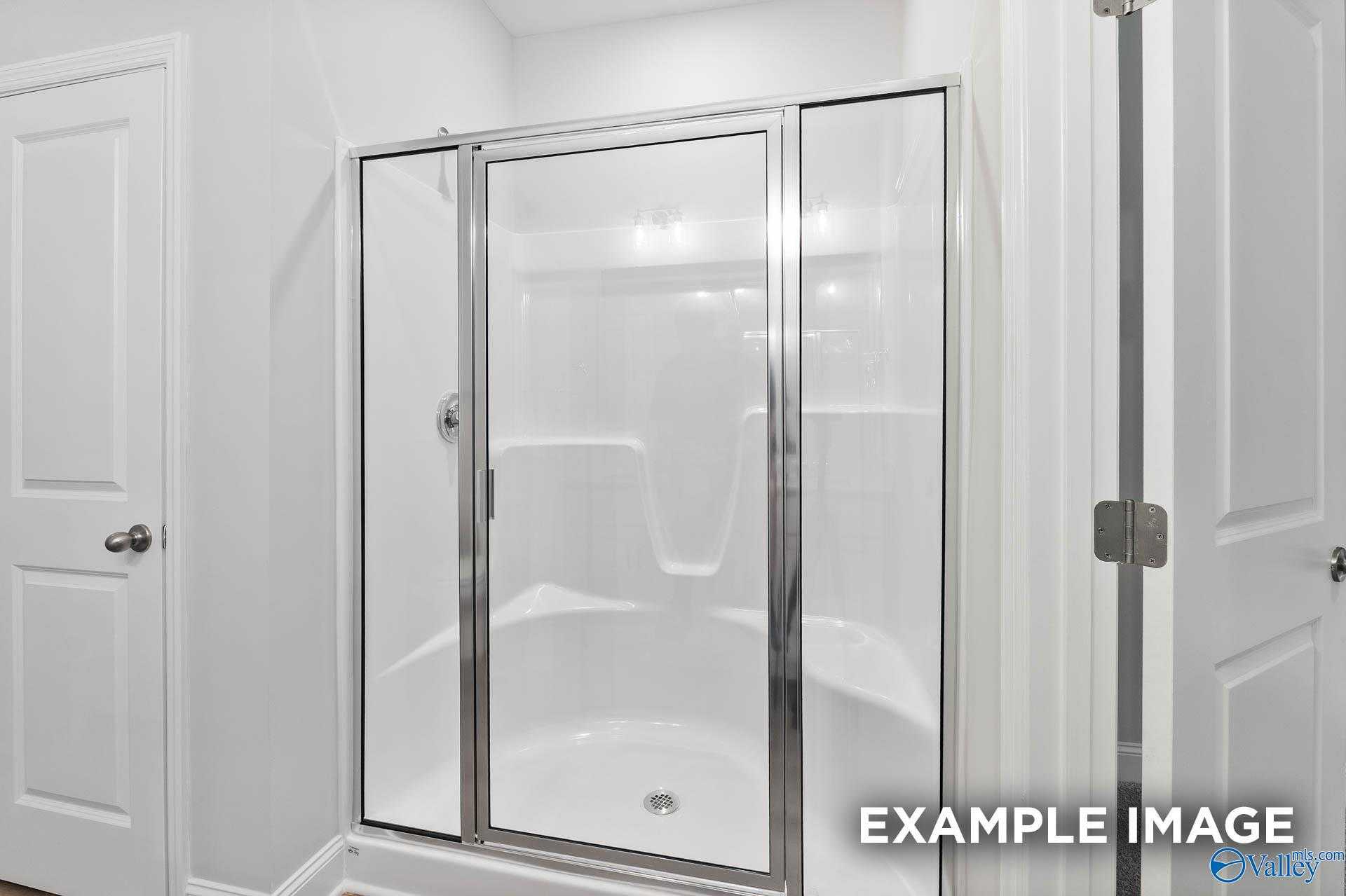 Modern frameless glass walk-in shower with white tile in Davidson Homes The Asheville C, Huntsville, Alabama