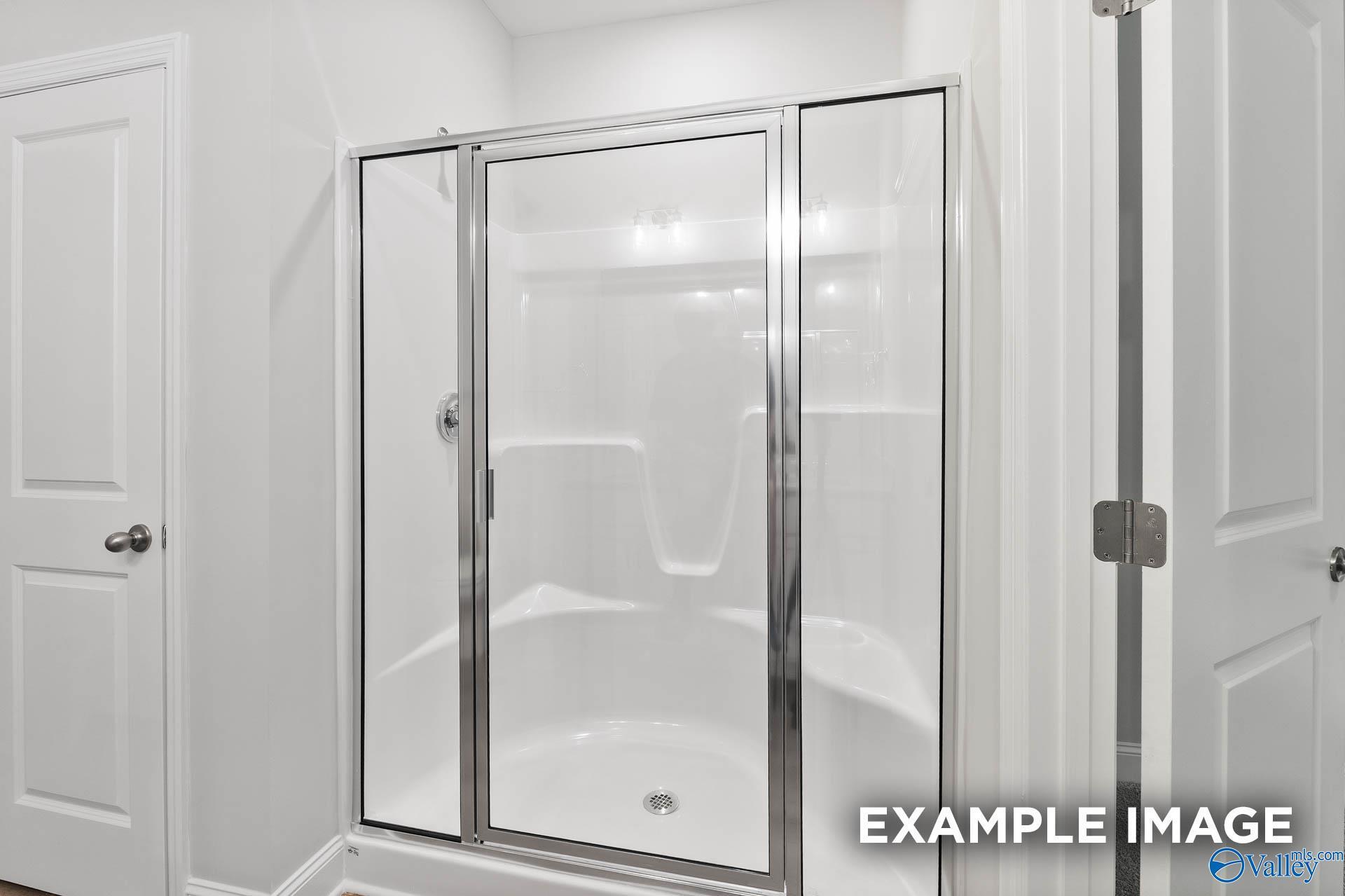 Modern frameless glass walk-in shower with white tiles in master bath, The Asheville floor plan by Davidson Homes, Huntsville AL