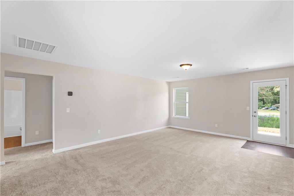 Bright master bedroom with beige walls, tan carpet, and sliding glass door to backyard in Davidson Homes The Washington, Phenix City