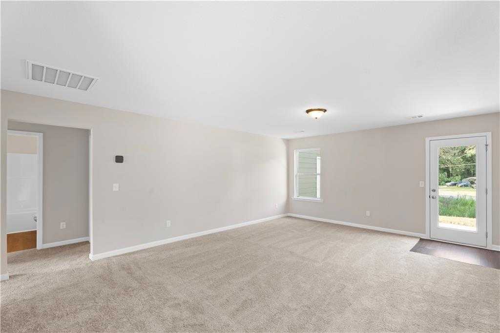 Bright master bedroom with beige walls, tan carpet, and sliding glass door to backyard in Davidson Homes The Washington, Phenix City