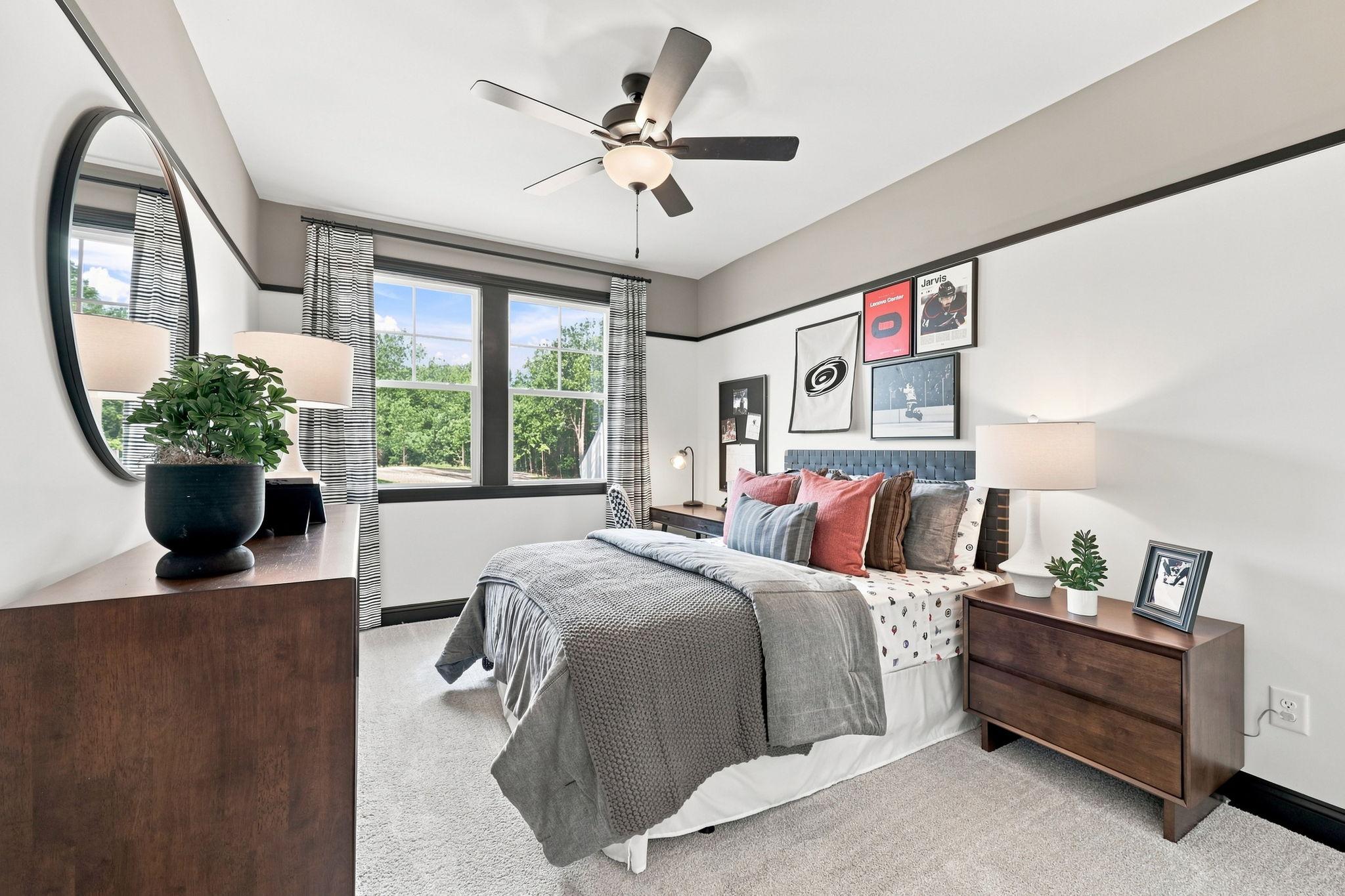 Spacious bedroom in The Barrington C by Davidson Homes featuring modern decor, dark wood furniture, and a comfortable bed.