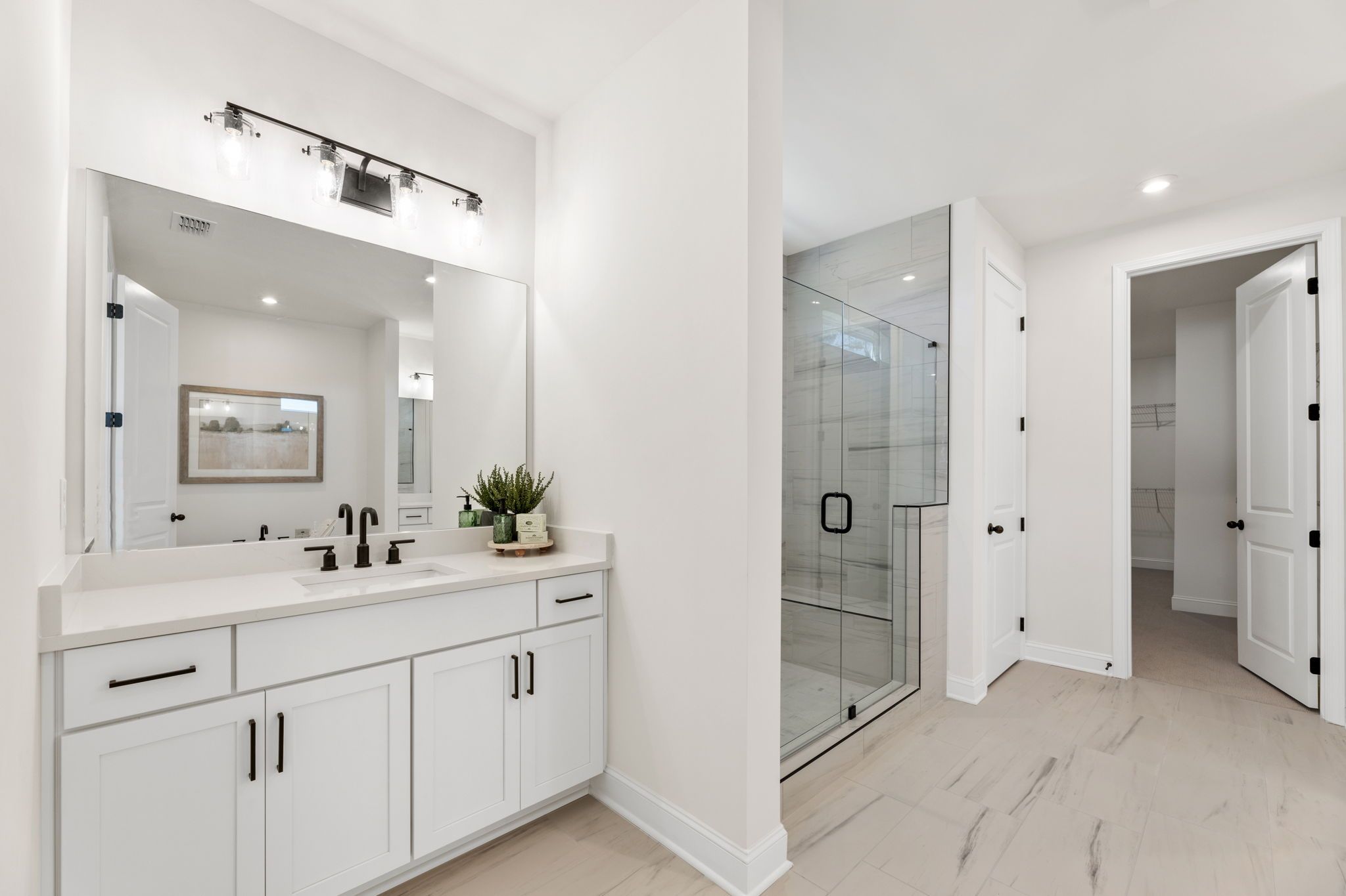 Modern primary bathroom at Fern Hollow in Buford GA featuring white double vanity, glass shower, and recessed lighting