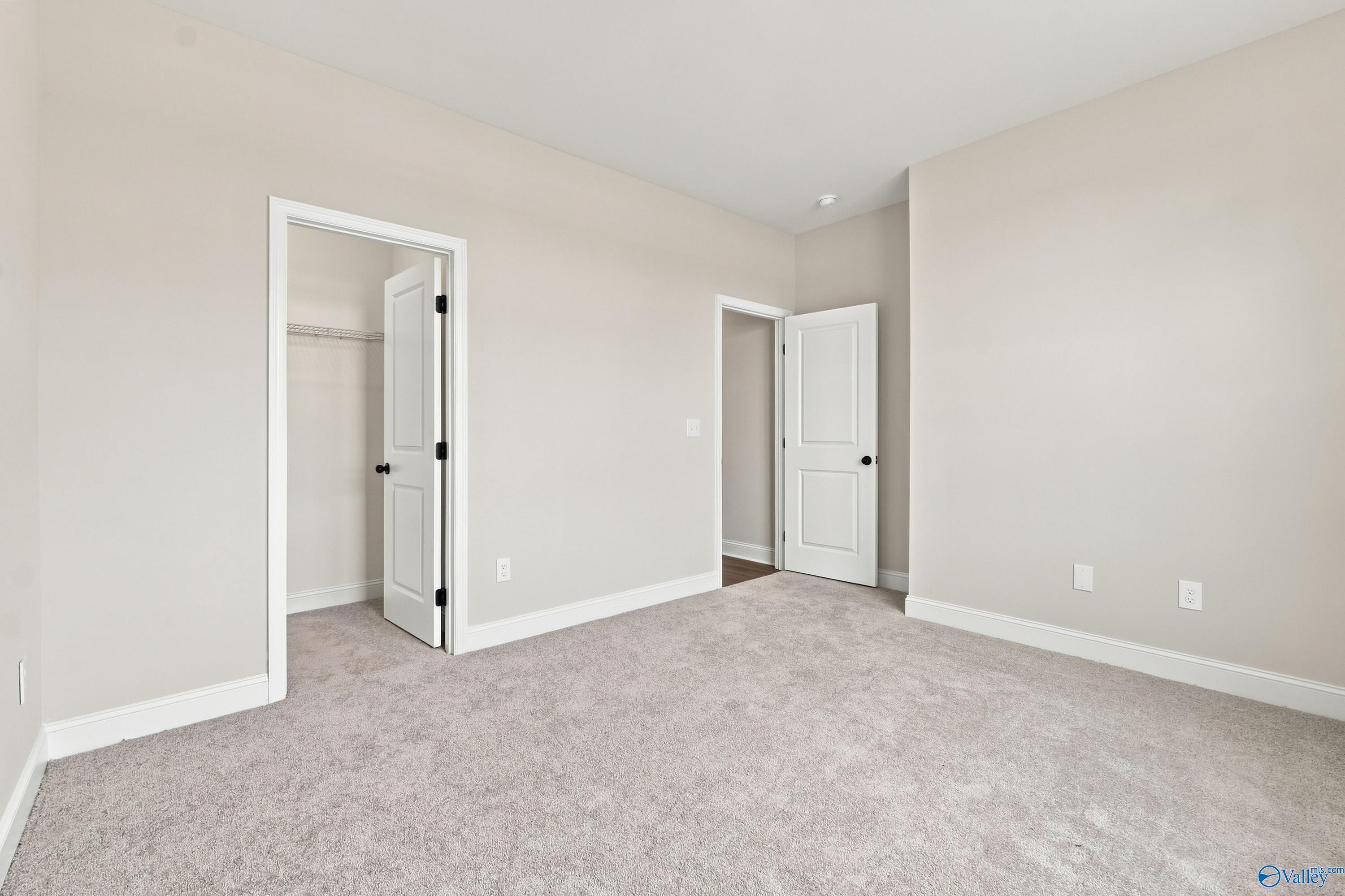 Spacious secondary bedroom with neutral carpet and walk-in closet in The Rockford B floor plan at Kendall Downs, Toney, AL.