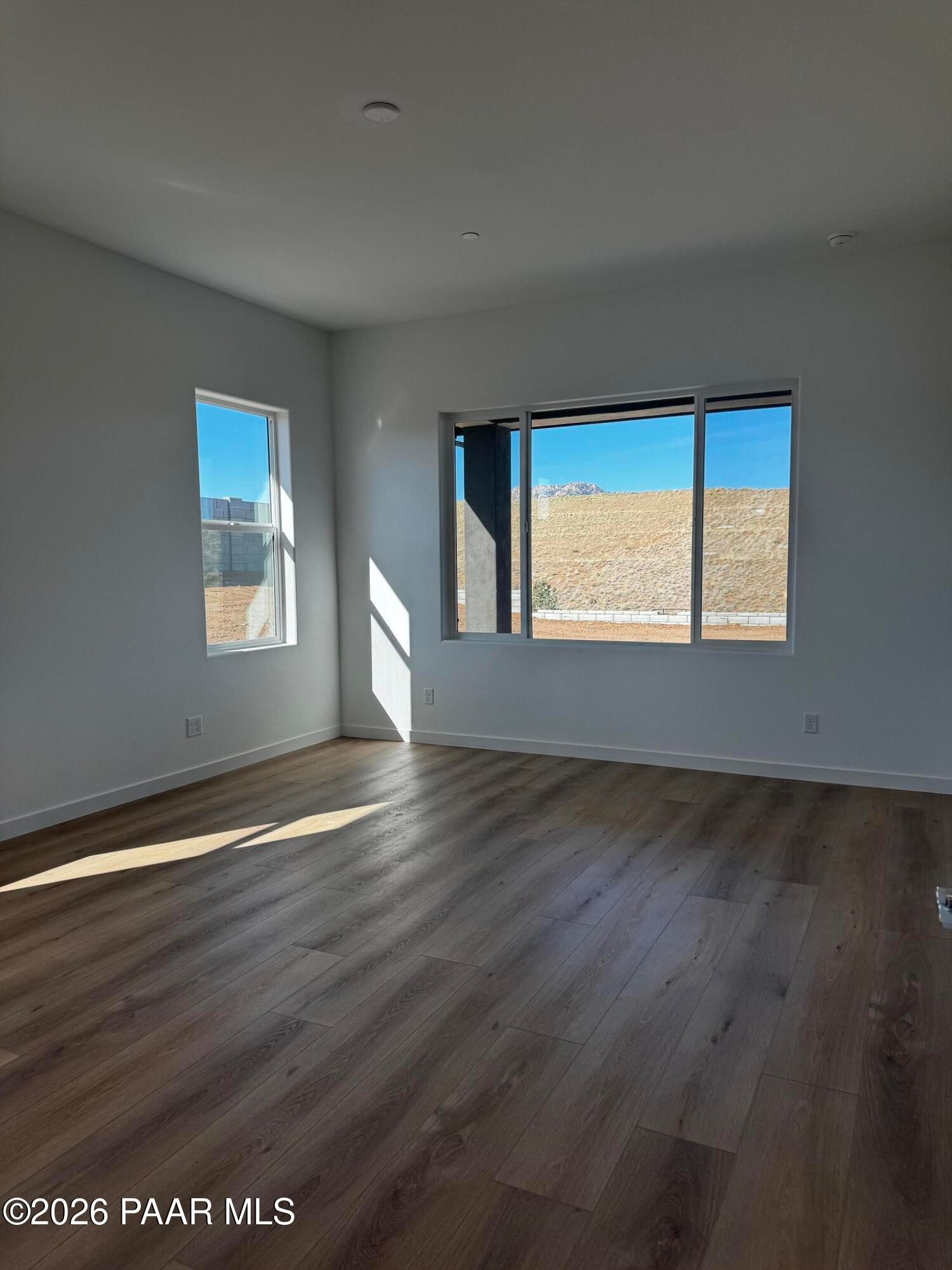 Bright empty great room with large windows overlooking desert landscape in The Blaze C home, Hidden Hills, Prescott, Arizona
