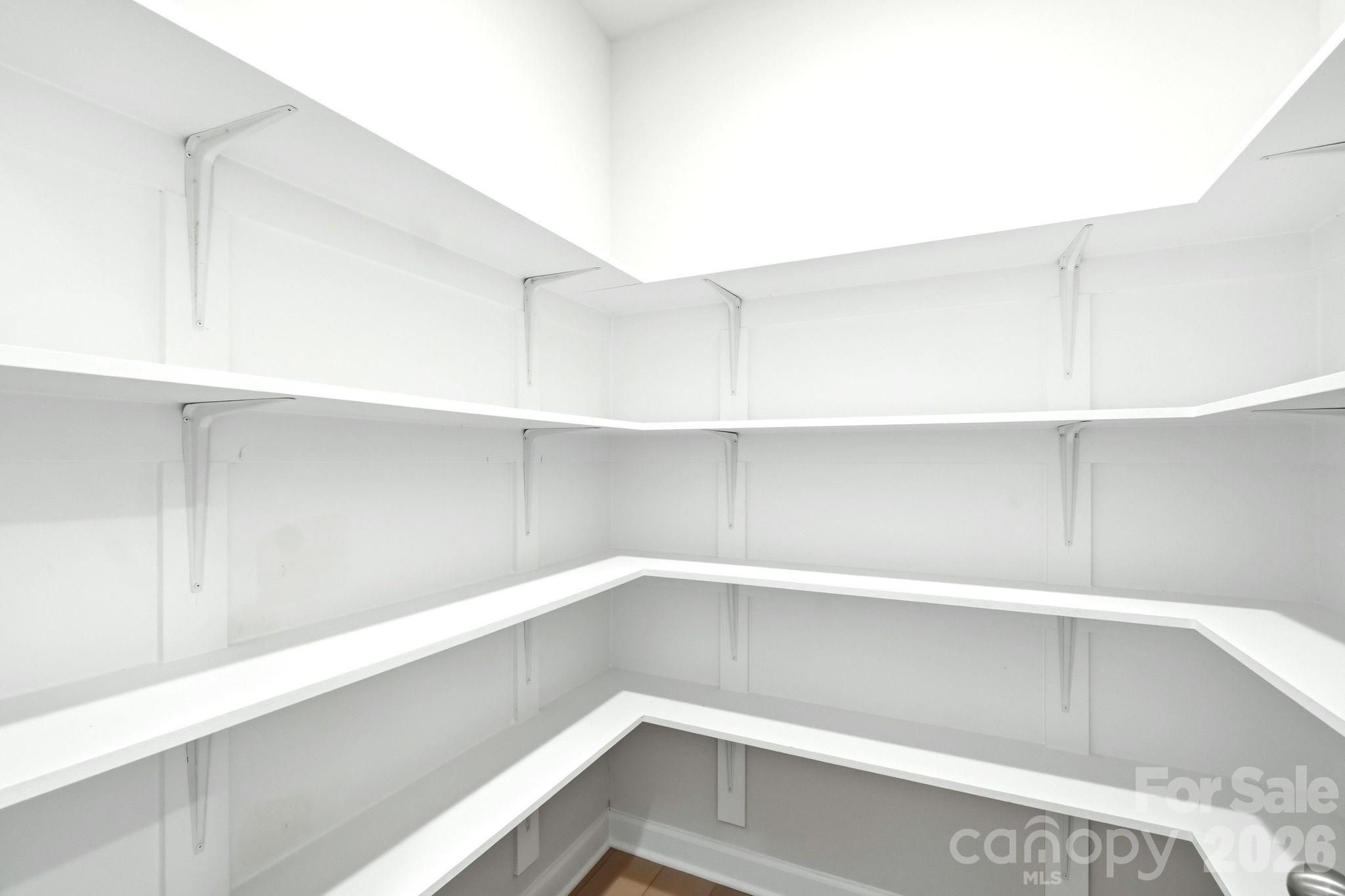 Walk-in pantry with white wrap-around shelving in The Magnolia B floor plan at Windgate in Mooresville, North Carolina.