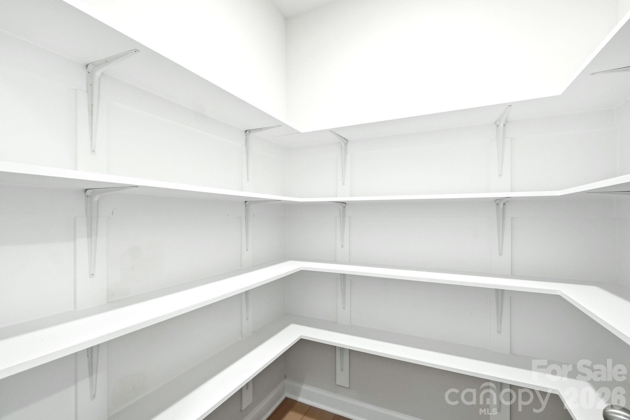Walk-in pantry with white wrap-around shelving in The Magnolia B floor plan at Windgate in Mooresville, North Carolina.