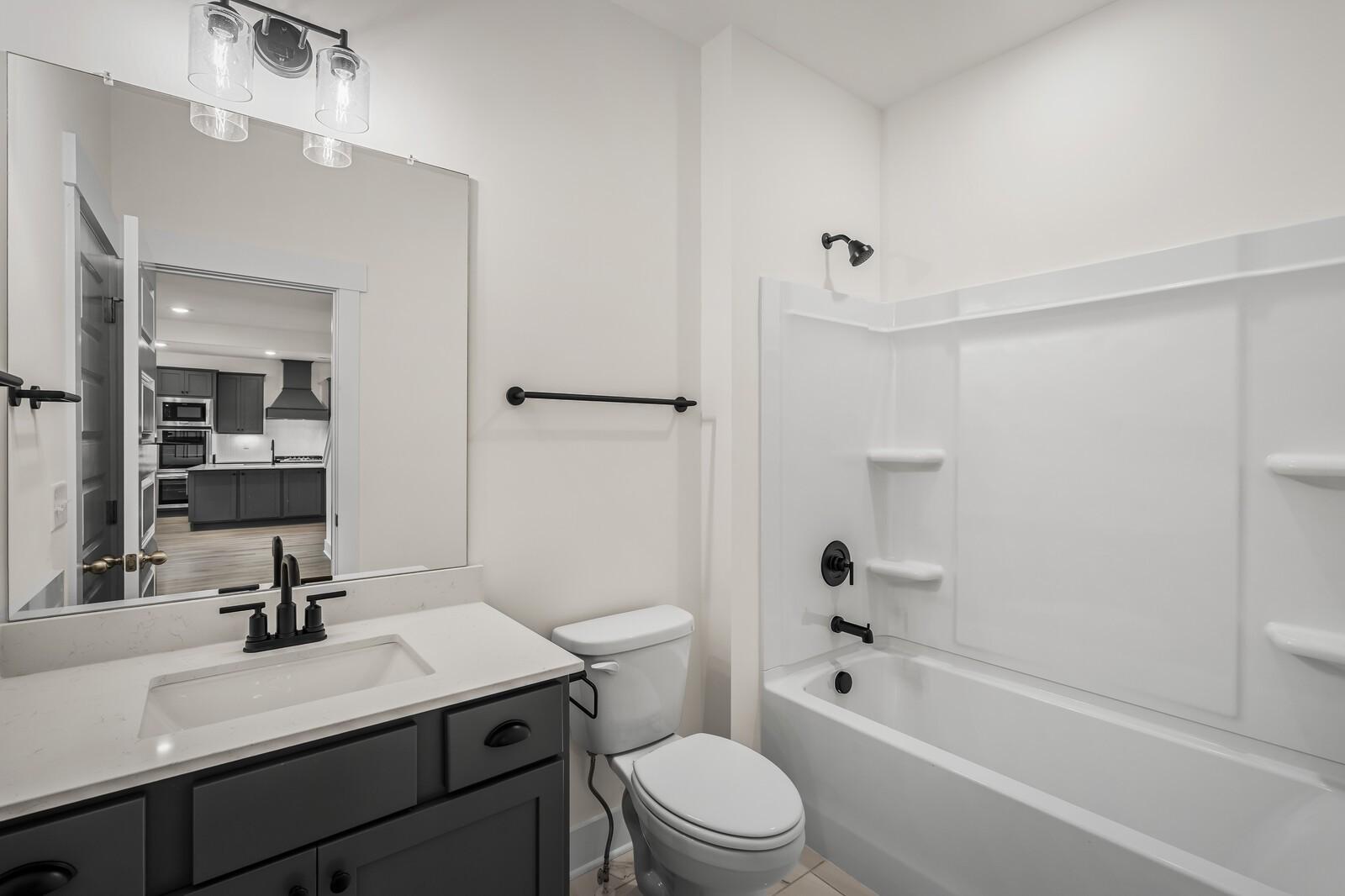 Modern bathroom with dark vanity, white quartz countertop, and tub-shower combo in Woods Crossing, Gallatin, Tennessee.