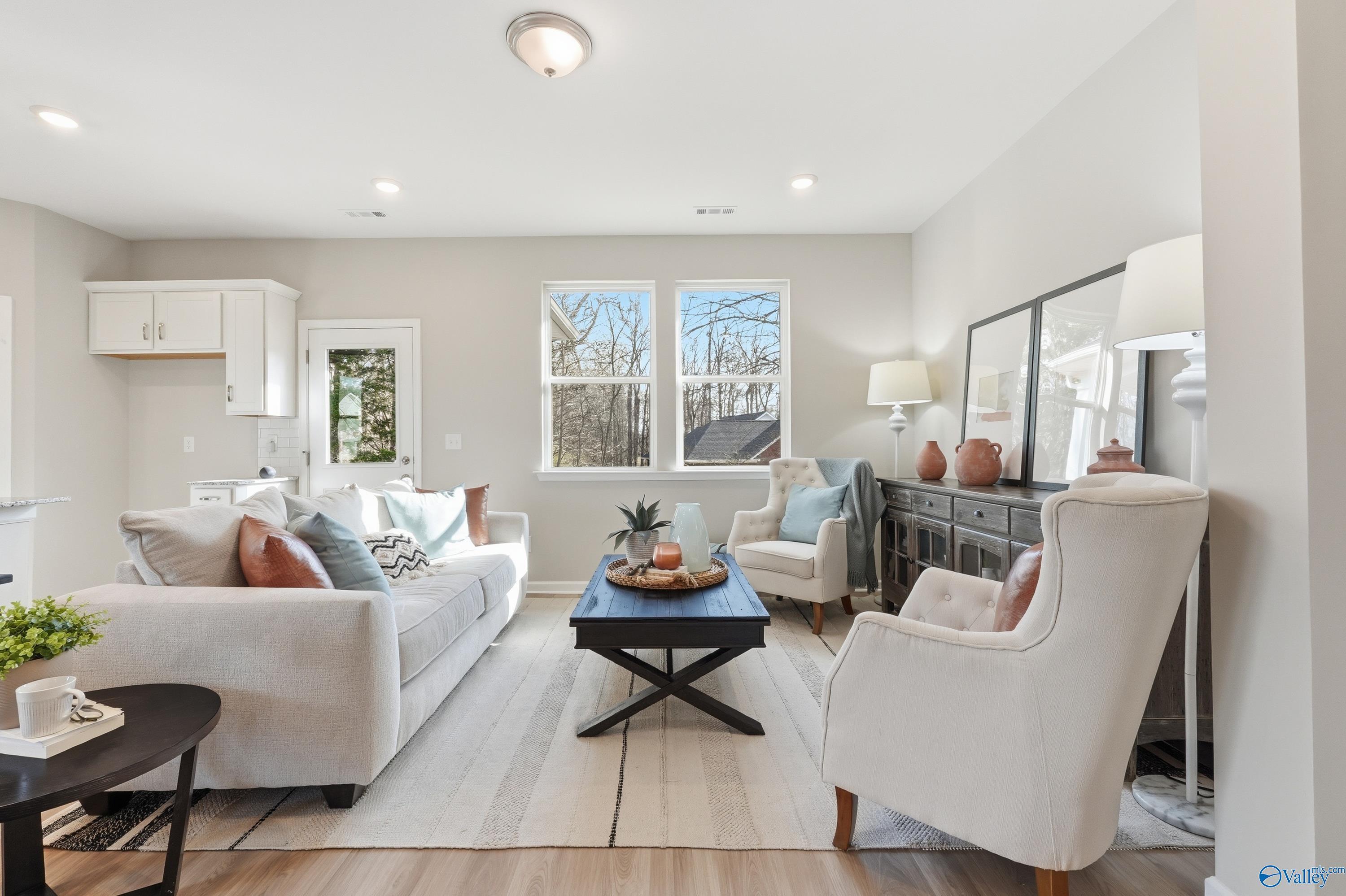 Cozy living room with gray sectional sofa, modern accents, and large windows in Davidson Homes The Polaris, Fayetteville, TN