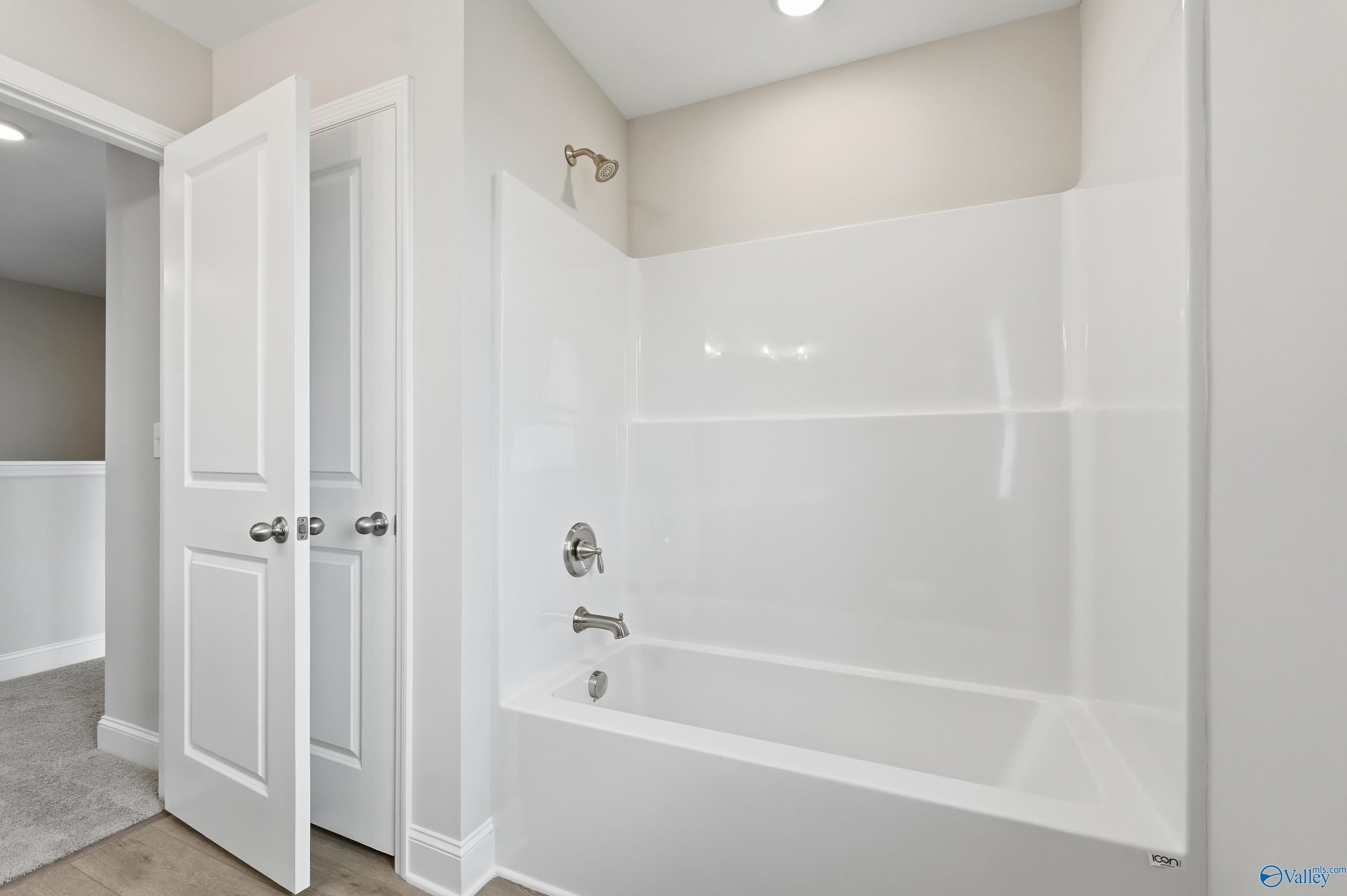 Modern master bathroom with white soaking tub, tiled shower enclosure, and double doors in Davidson Homes Shelby B, New Market, AL