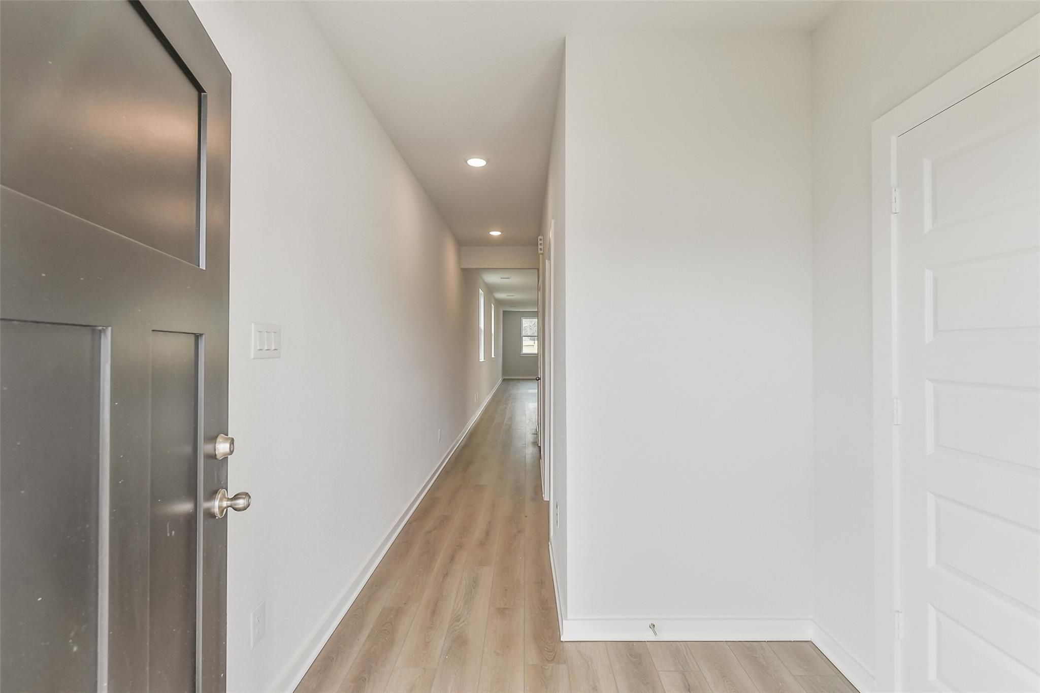Bright hallway with laminate wood flooring and white walls in Davidson Homes The Frio G, Liberty Estates, Cleveland Texas