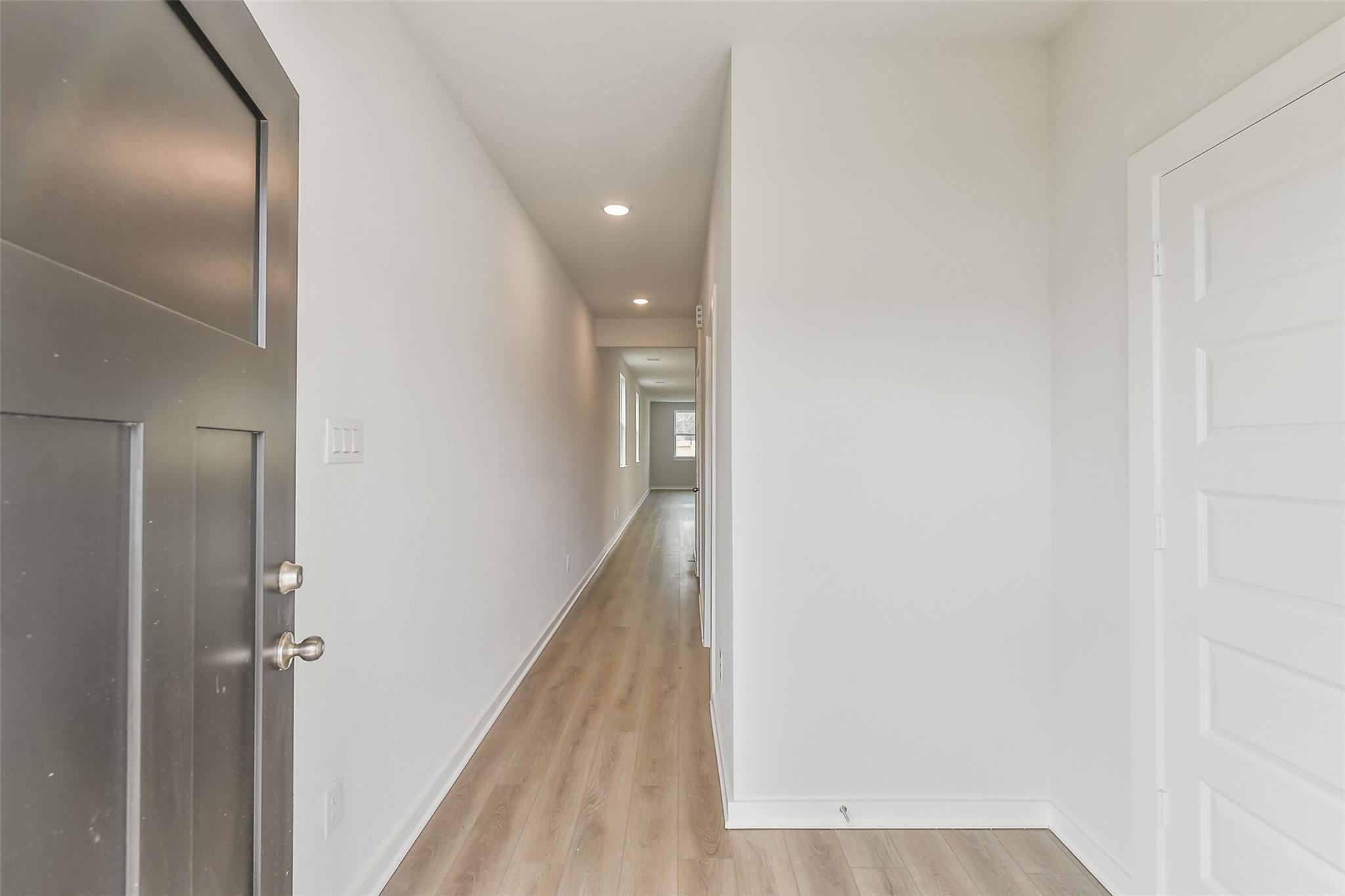 Bright hallway with laminate wood flooring and white walls in Davidson Homes The Frio G, Liberty Estates, Cleveland Texas
