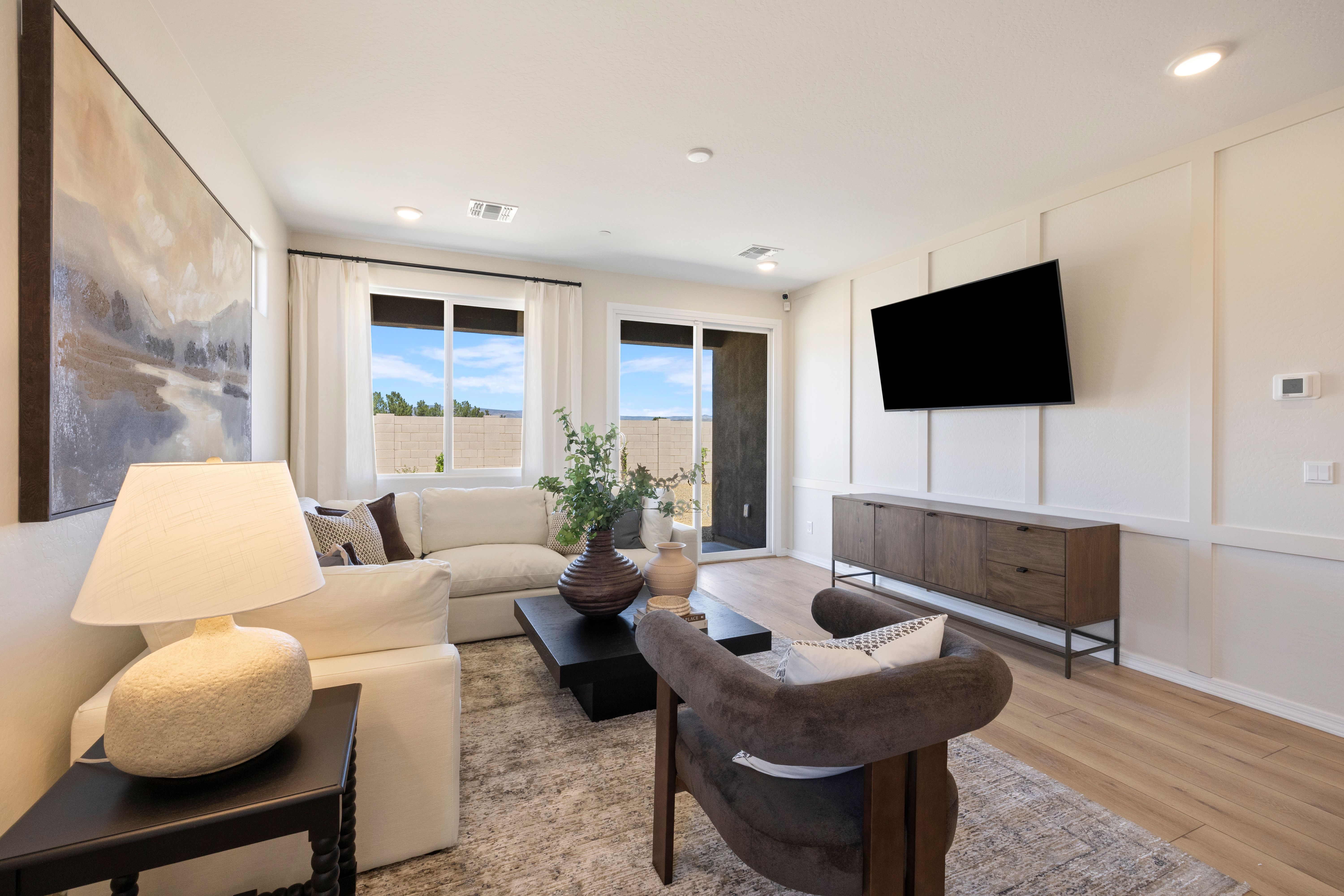 Spacious living room at Vineyards at Cottonwood in Cottonwood AZ with beige sofa, mounted TV, sliding doors to desert view, hardwood floors