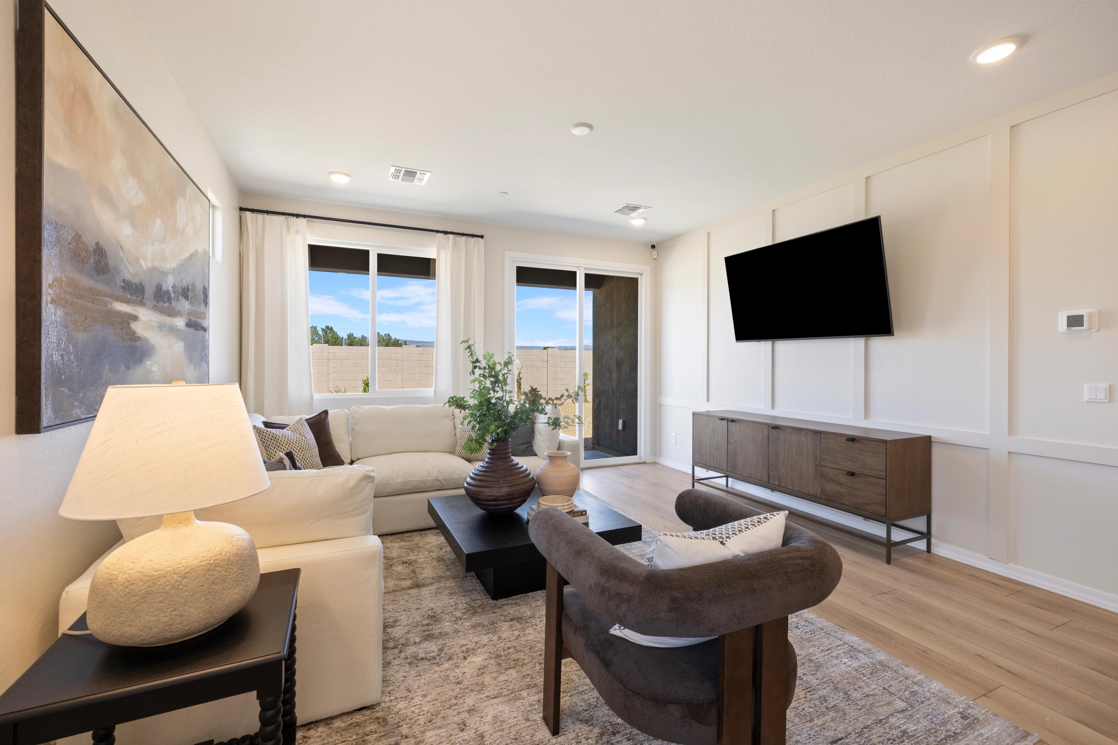 Spacious living room at Vineyards at Cottonwood in Cottonwood AZ with beige sofa, mounted TV, sliding doors to desert view, hardwood floors