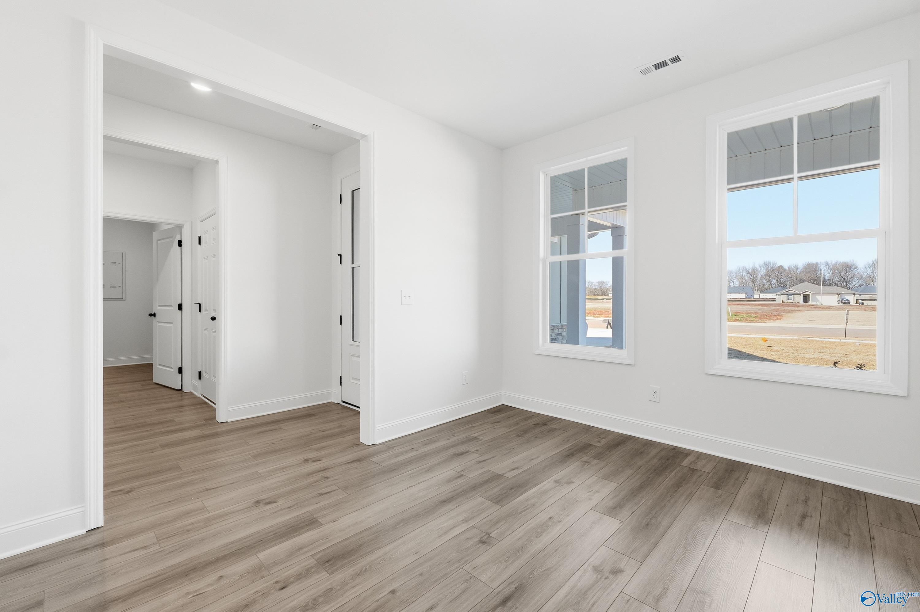 Bright bedroom with hardwood floors, arched doorway, and large windows overlooking wooded yard in Davidson Homes Rockford D, Hazel Green, AL