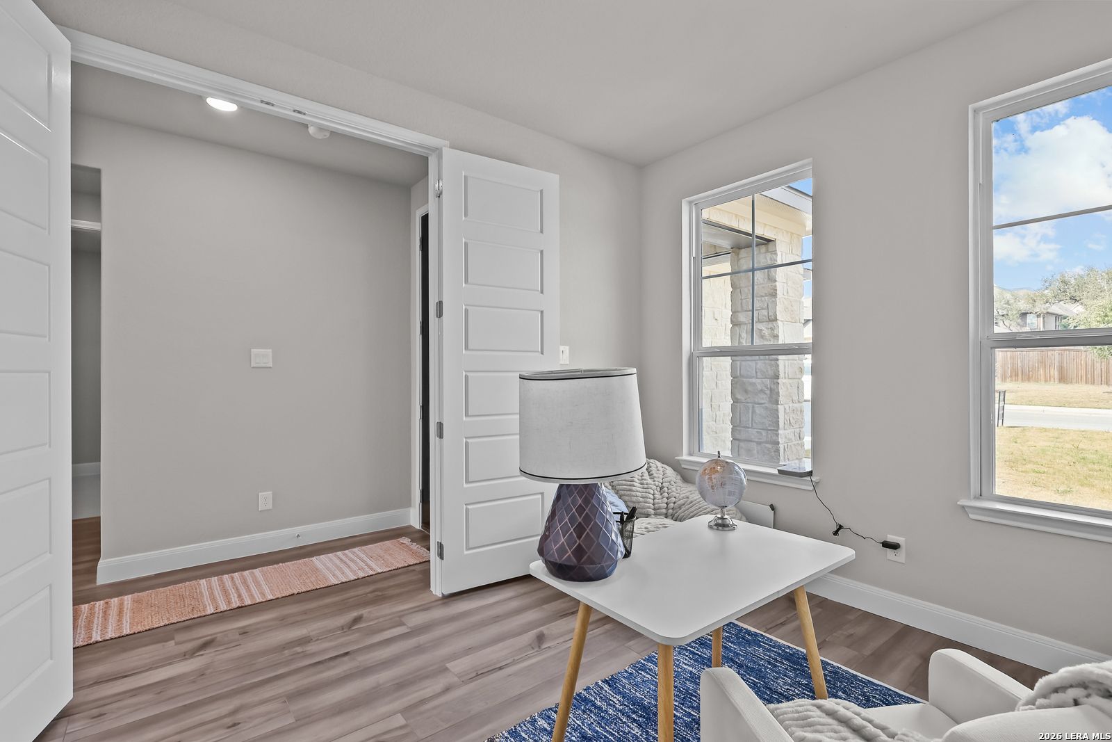 Cozy home nook with wooden floors, large windows, accent lamp, and armchair in Davidson Homes The Rockford G, Ladera, Texas