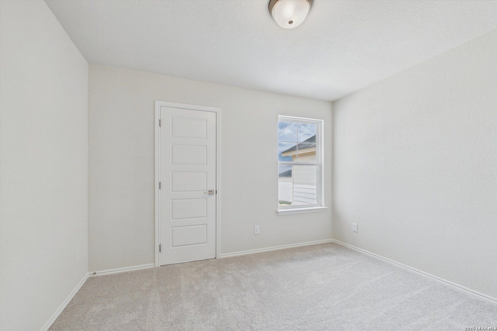 Bright, carpeted bedroom with neutral walls in The Charlotte B floor plan at Meadows at Oak Creek, San Antonio, Texas.