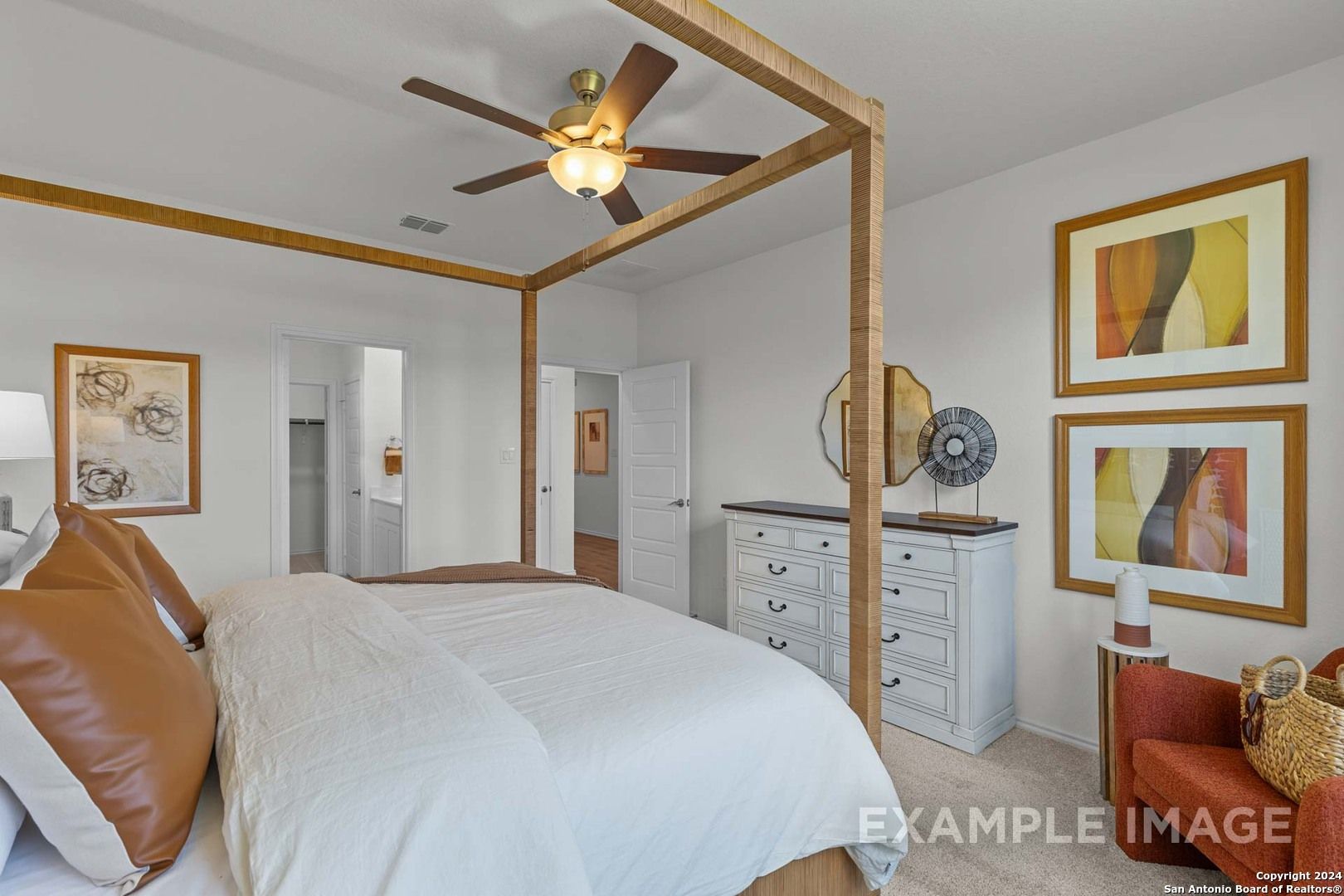 Elegant master bedroom with canopy bed, ceiling fan, white dresser, and abstract art in Davidson Homes The Daphne K, San Antonio