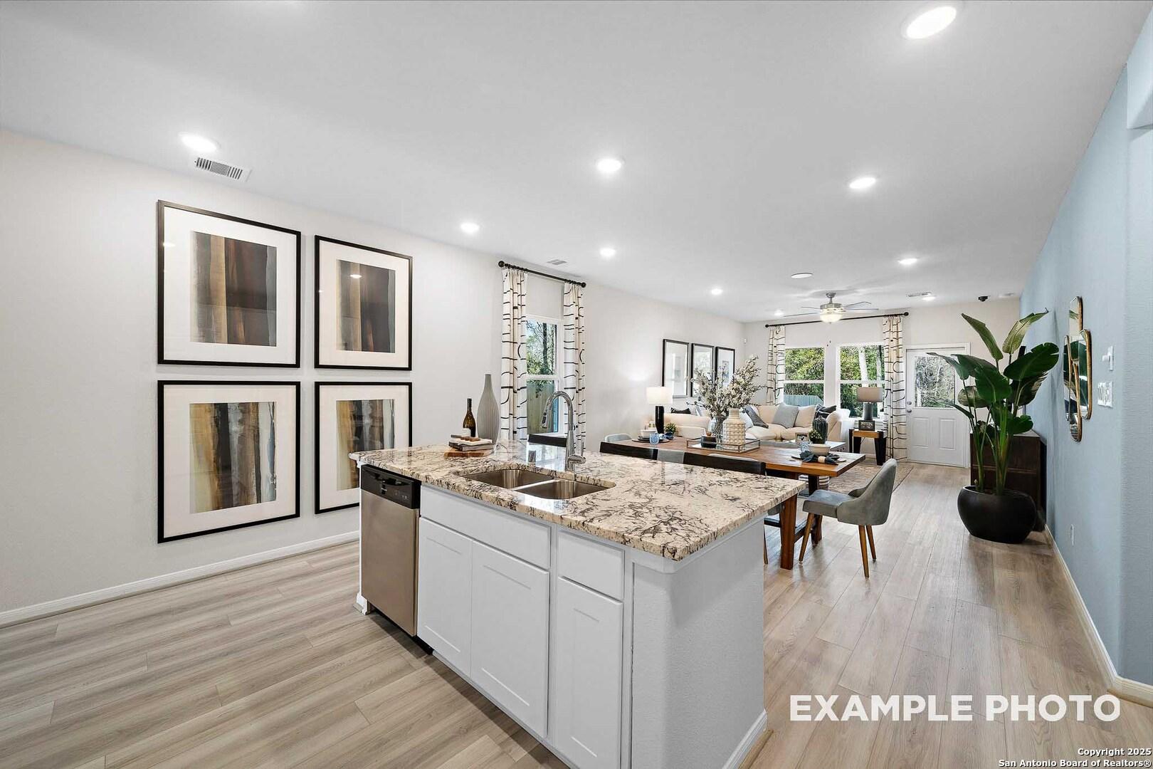 Bright open-concept kitchen with white cabinets, quartz island sink, and dining area in The San Marcos D, Davidson Homes, San Antonio