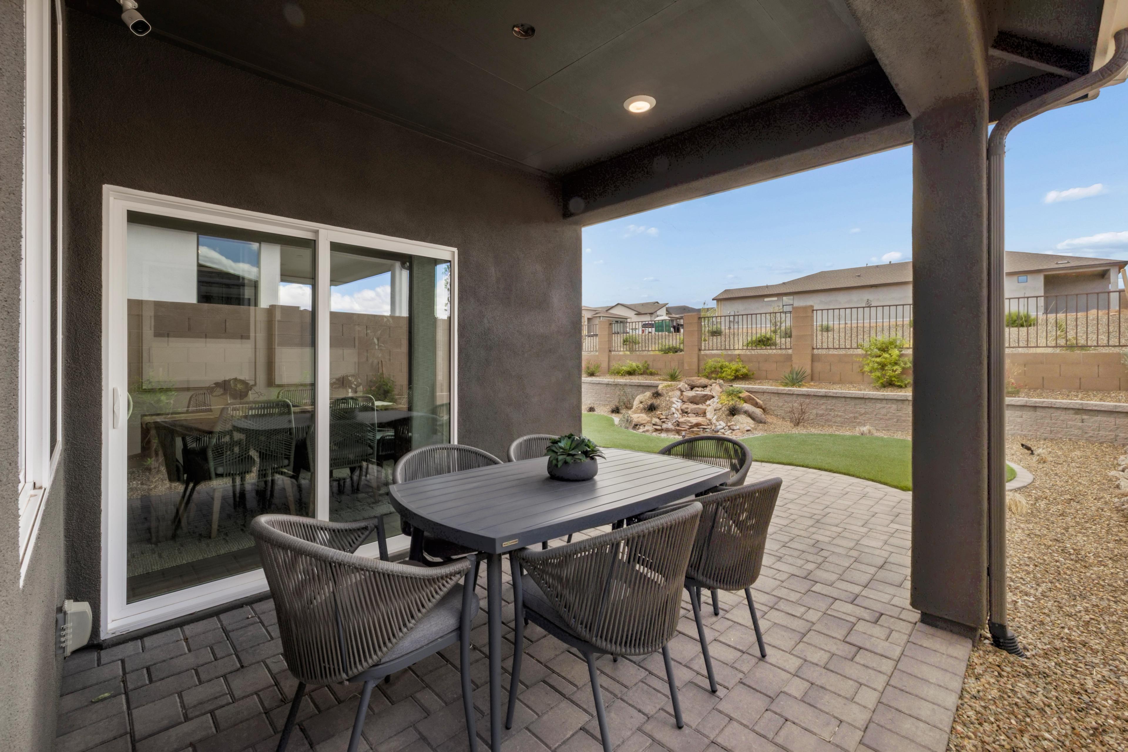 Covered patio with wicker dining set at South Ranch in Prescott AZ featuring rock waterfall, turf and desert landscape
