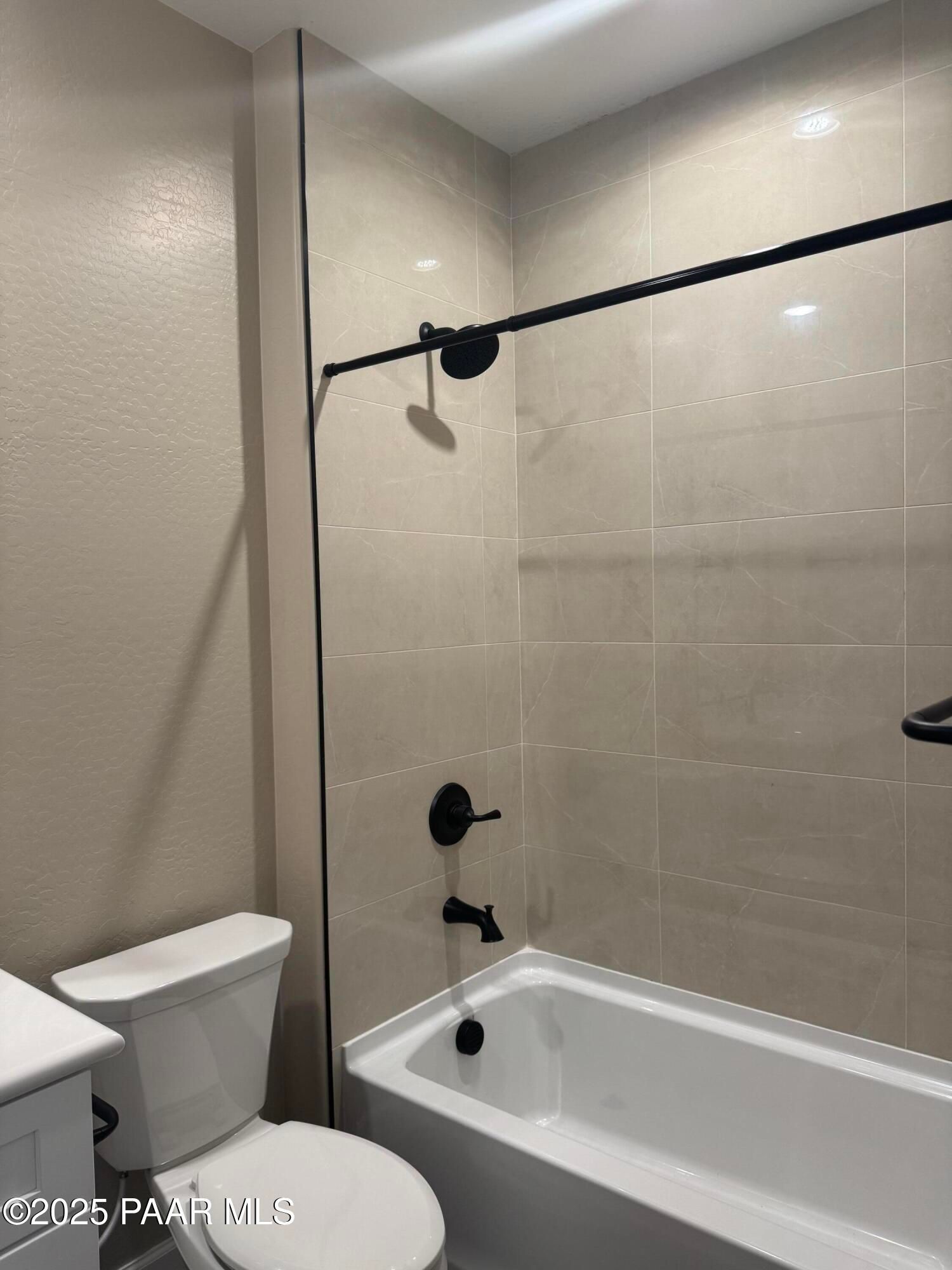 Modern master bathroom with soaking tub, glass shower door, black fixtures, and beige tile in Evermore Homes The Sunrise A, Prescott Valley
