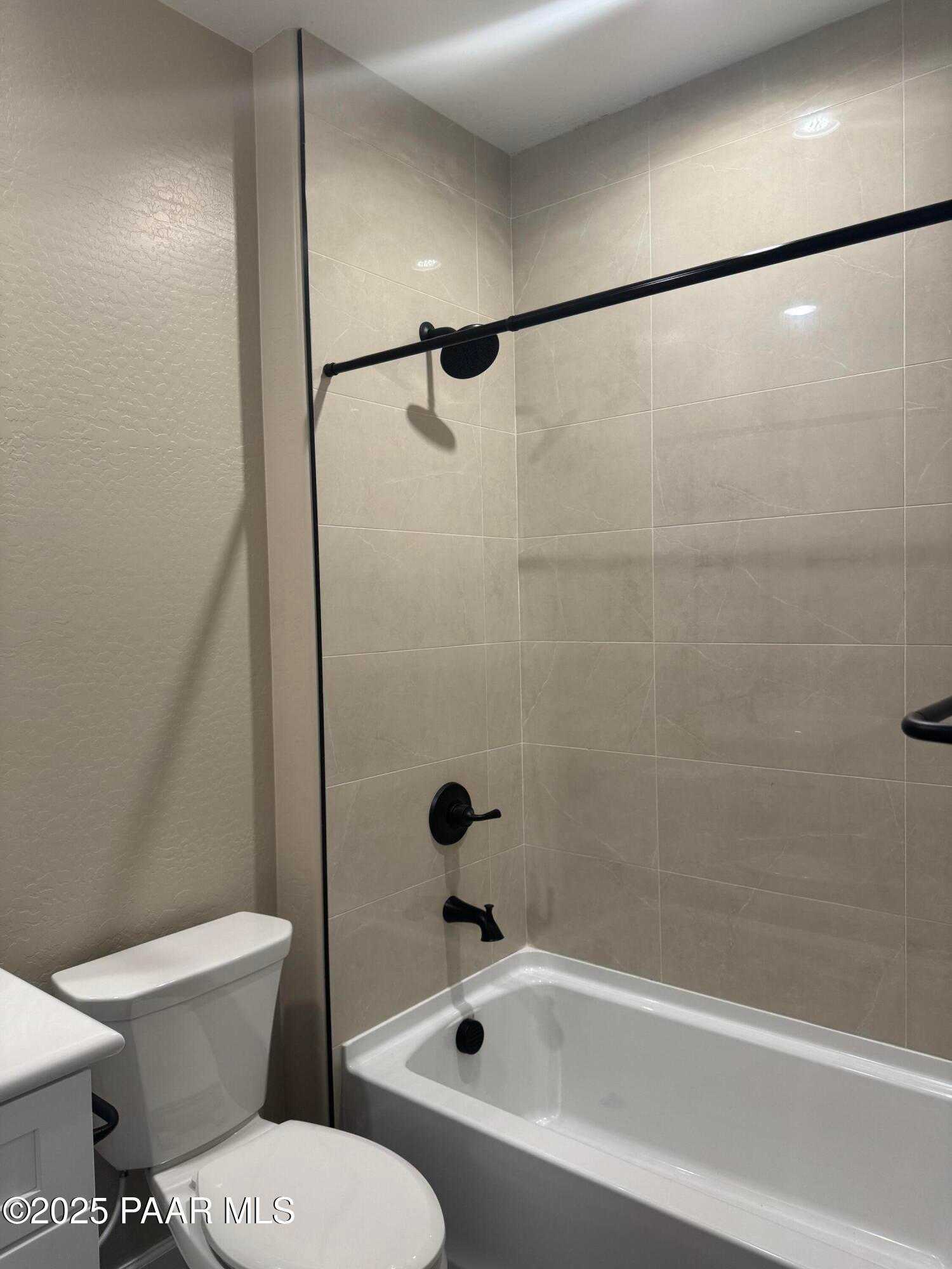 Modern master bathroom with soaking tub, glass shower door, black fixtures, and beige tile in Evermore Homes The Sunrise A, Prescott Valley