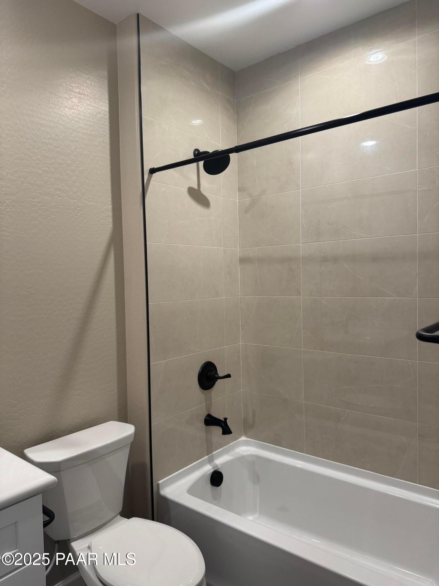 Modern master bathroom with soaking tub, glass shower door, black fixtures, and beige tile in Evermore Homes The Sunrise A, Prescott Valley