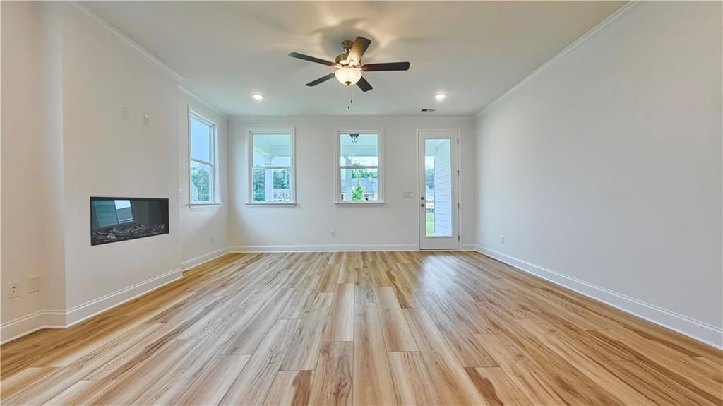 Bright living room with fireplace and wood-look flooring in The Glenwood A floor plan at Wehunt Meadows, Hoschton, GA.
