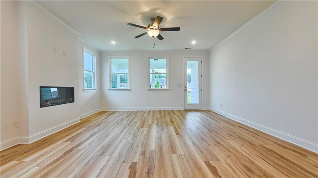 Bright living room with fireplace and wood-look flooring in The Glenwood A floor plan at Wehunt Meadows, Hoschton, GA.