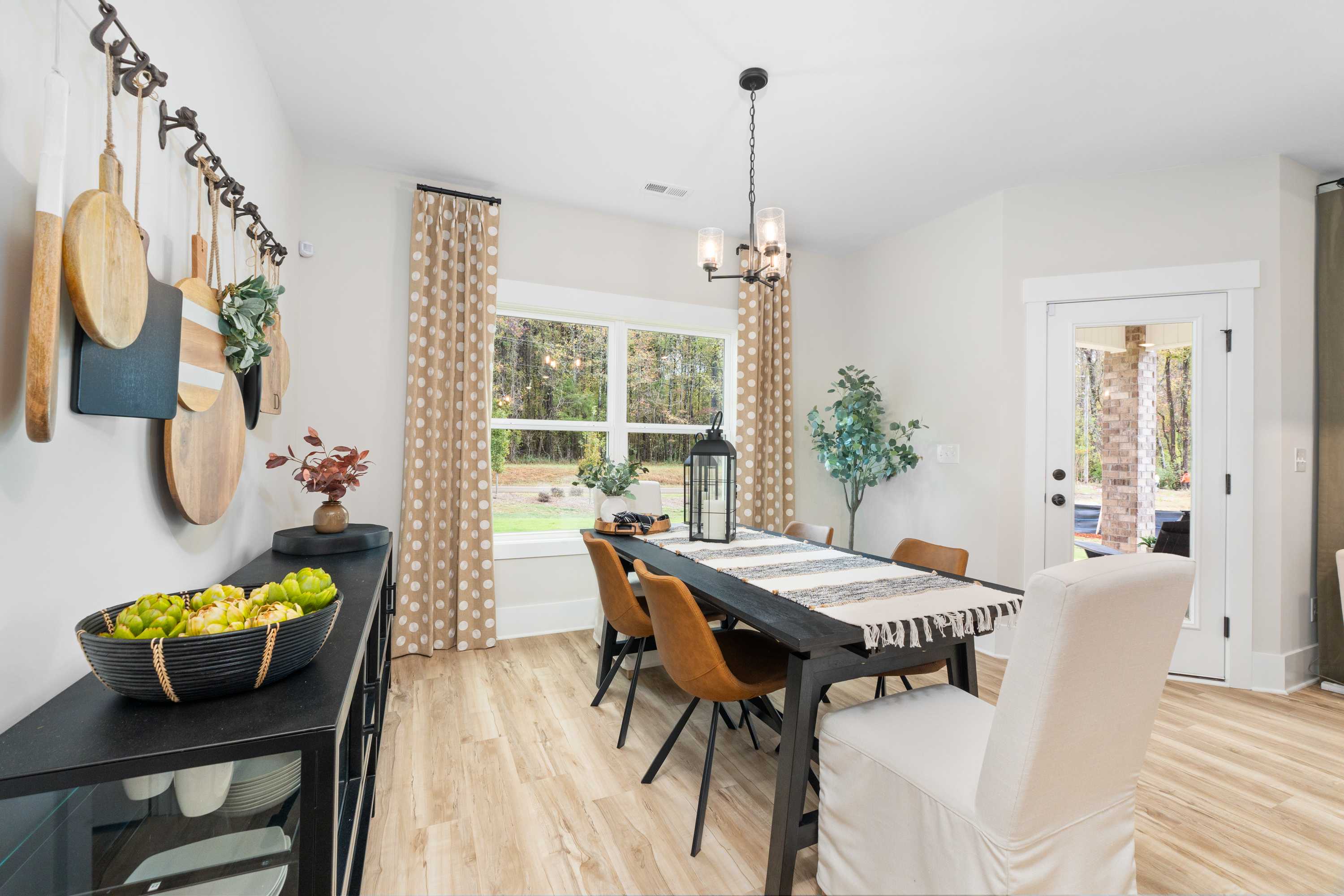 Elegant dining room in Spragins Cove, Huntsville AL with wooden table, upholstered chairs, fruit bowl, wall decor and window to outdoors