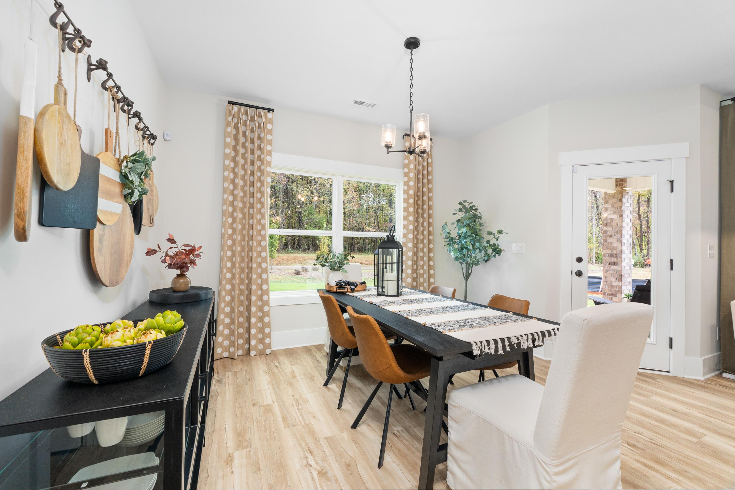 Elegant dining room in Spragins Cove, Huntsville AL with wooden table, upholstered chairs, fruit bowl, wall decor and window to outdoors