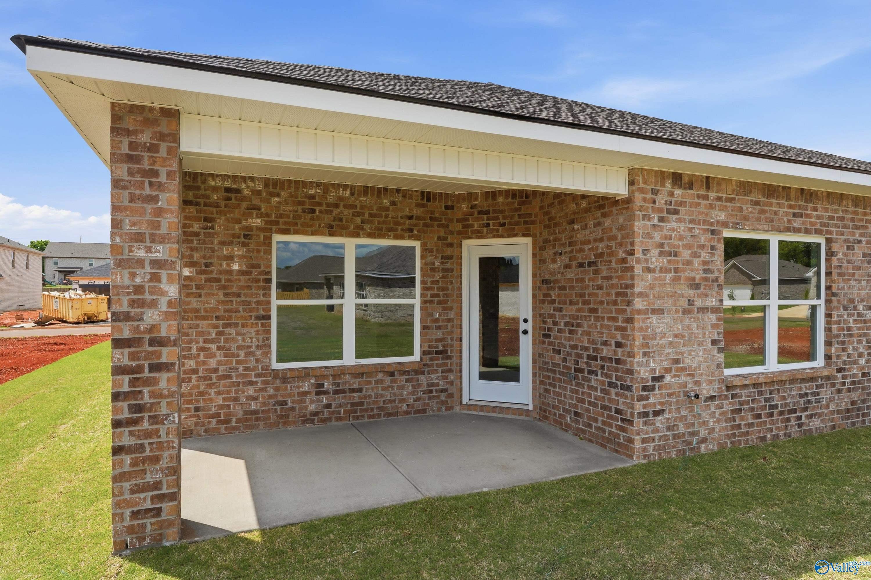 Brick single-story home with covered front porch, double windows, white door, and green lawn in Lynn Meadows, Meridianville, Alabama