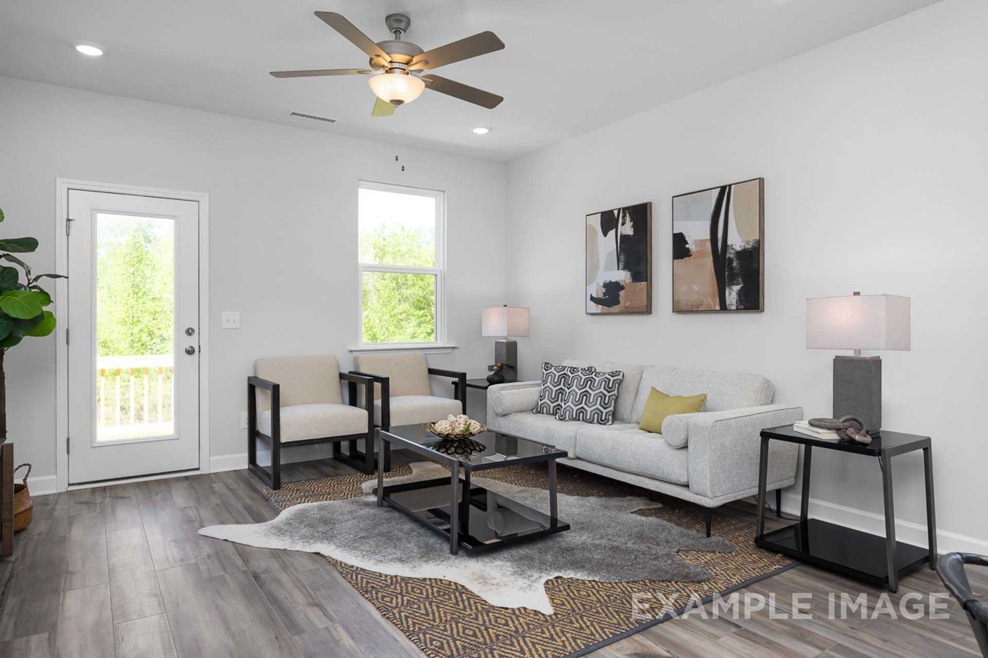 Spacious modern living room in The Carter B with beige sofa, abstract wall art, French doors to porch, and hardwood floors
