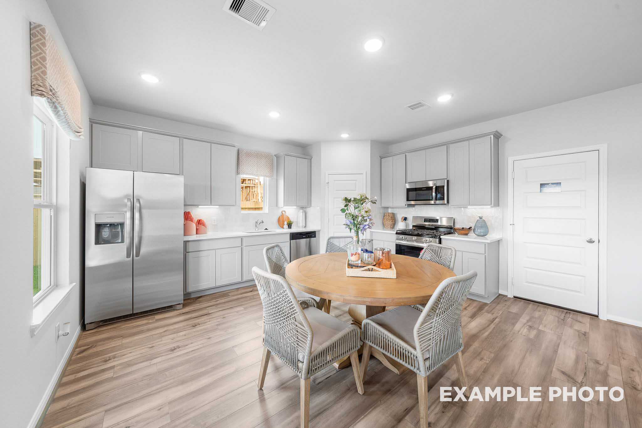 Spacious Trinity kitchen by Davidson Homes featuring light gray cabinets, stainless steel appliances, and round wood dining table