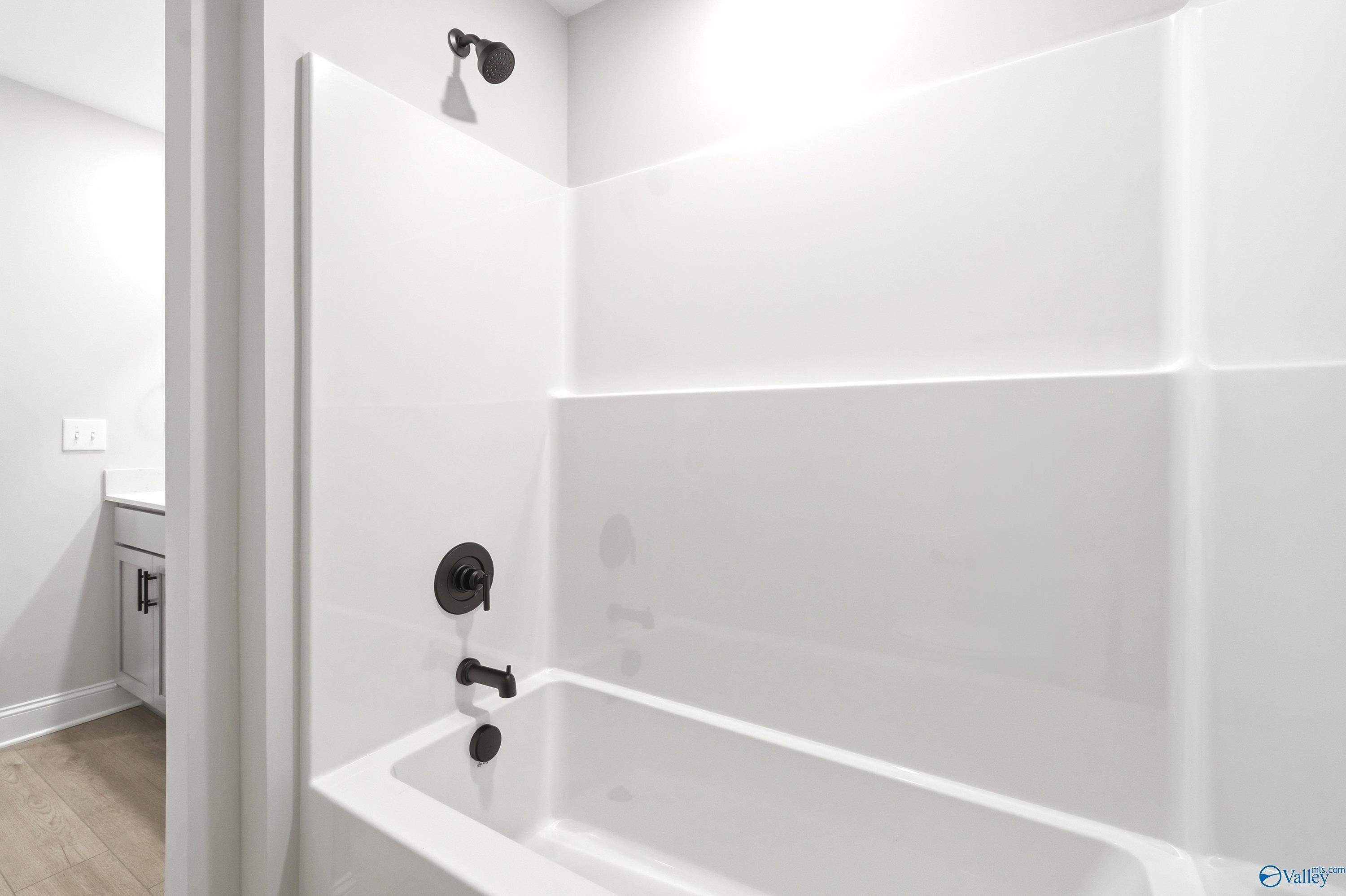 Modern bathroom with white tub and shower combo featuring matte black fixtures in a Davidson Homes Russell A floor plan.