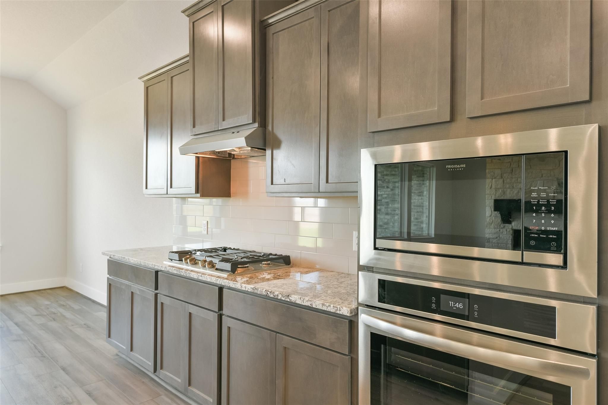 Modern kitchen featuring gray shaker cabinets, granite countertops, stainless steel oven and cooktop in Davidson Homes The Edward A, Lago Mar, Texas City