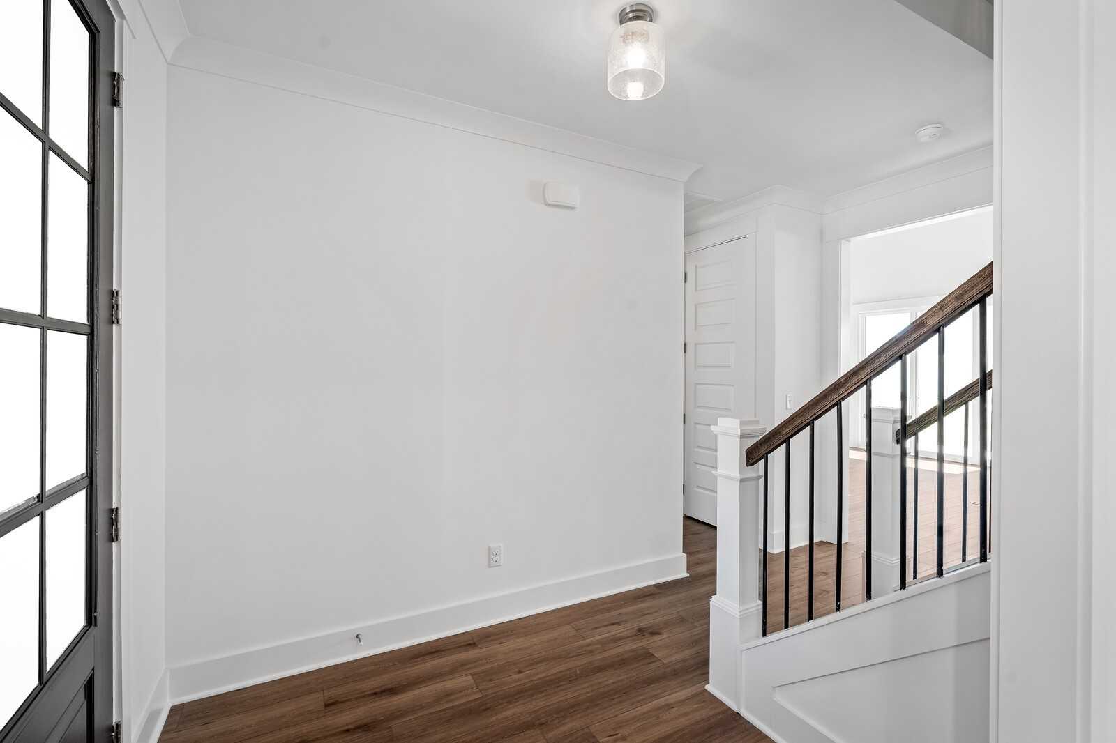 Bright foyer with hardwood floors and modern black metal staircase in The Hawkins 4-bedroom home, Murfreesboro, TN