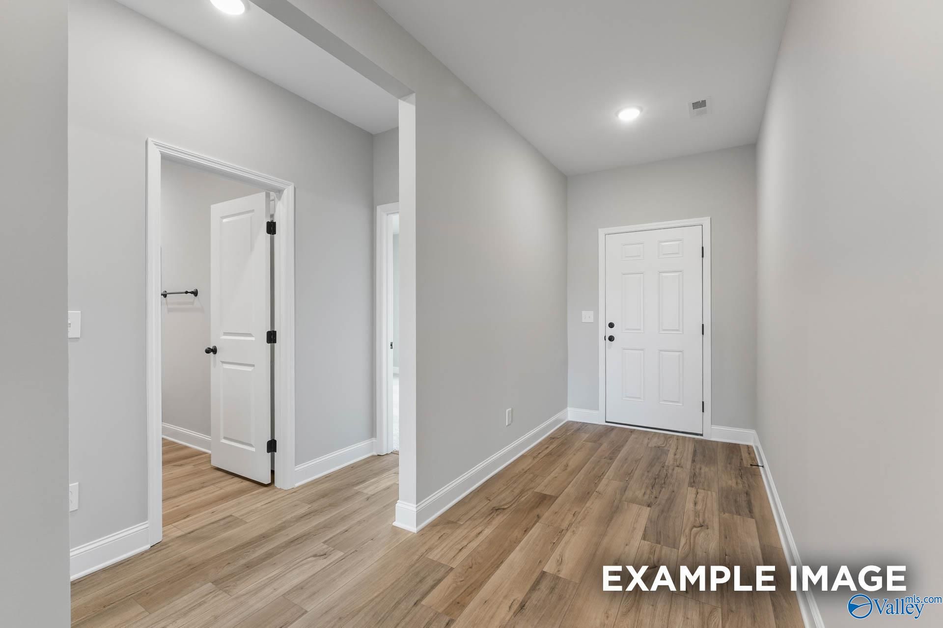 Bright hallway with white doors to bathroom and bedroom, light wood floors in Davidson Homes The Daphne C, Athens, Alabama