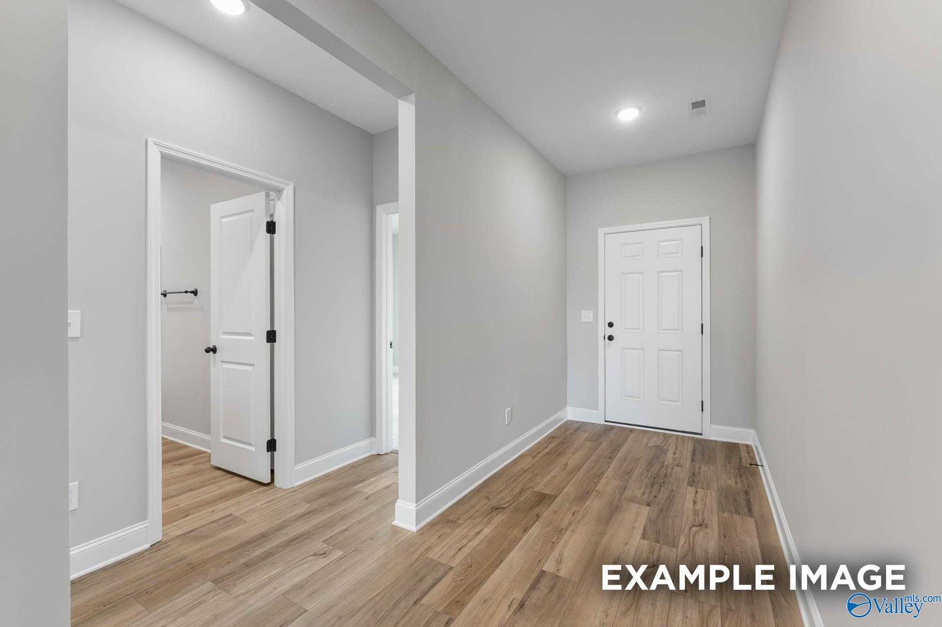 Bright hallway with white doors to bathroom and bedroom, light wood floors in Davidson Homes The Daphne C, Athens, Alabama