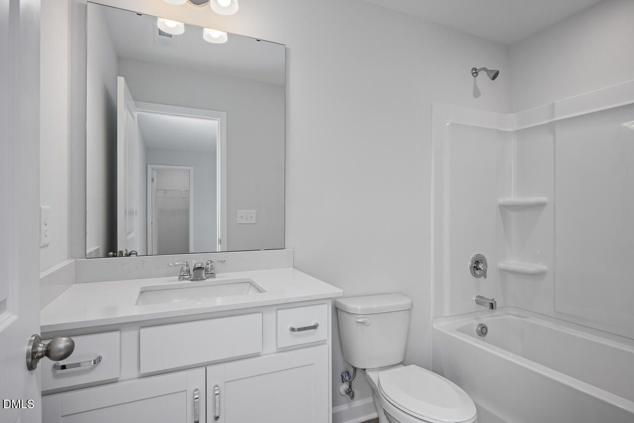 Modern white bathroom featuring double-sink vanity, large mirror, tub-shower combo in Davidson Homes Hickory II B, Zebulon, NC