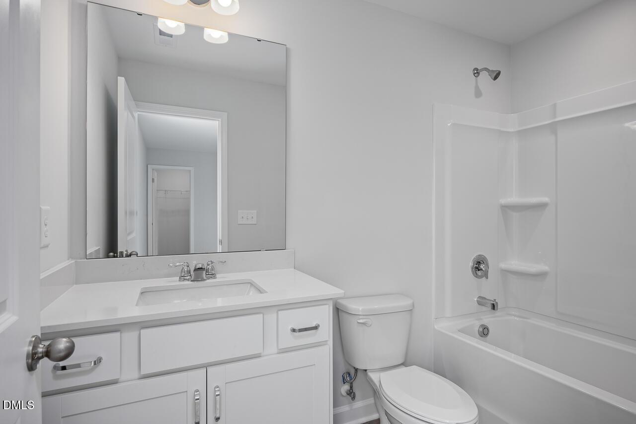 Bright modern bathroom with white vanity, large mirror, tub-shower combo in Davidson Homes The Hickory II B, Zebulon, NC