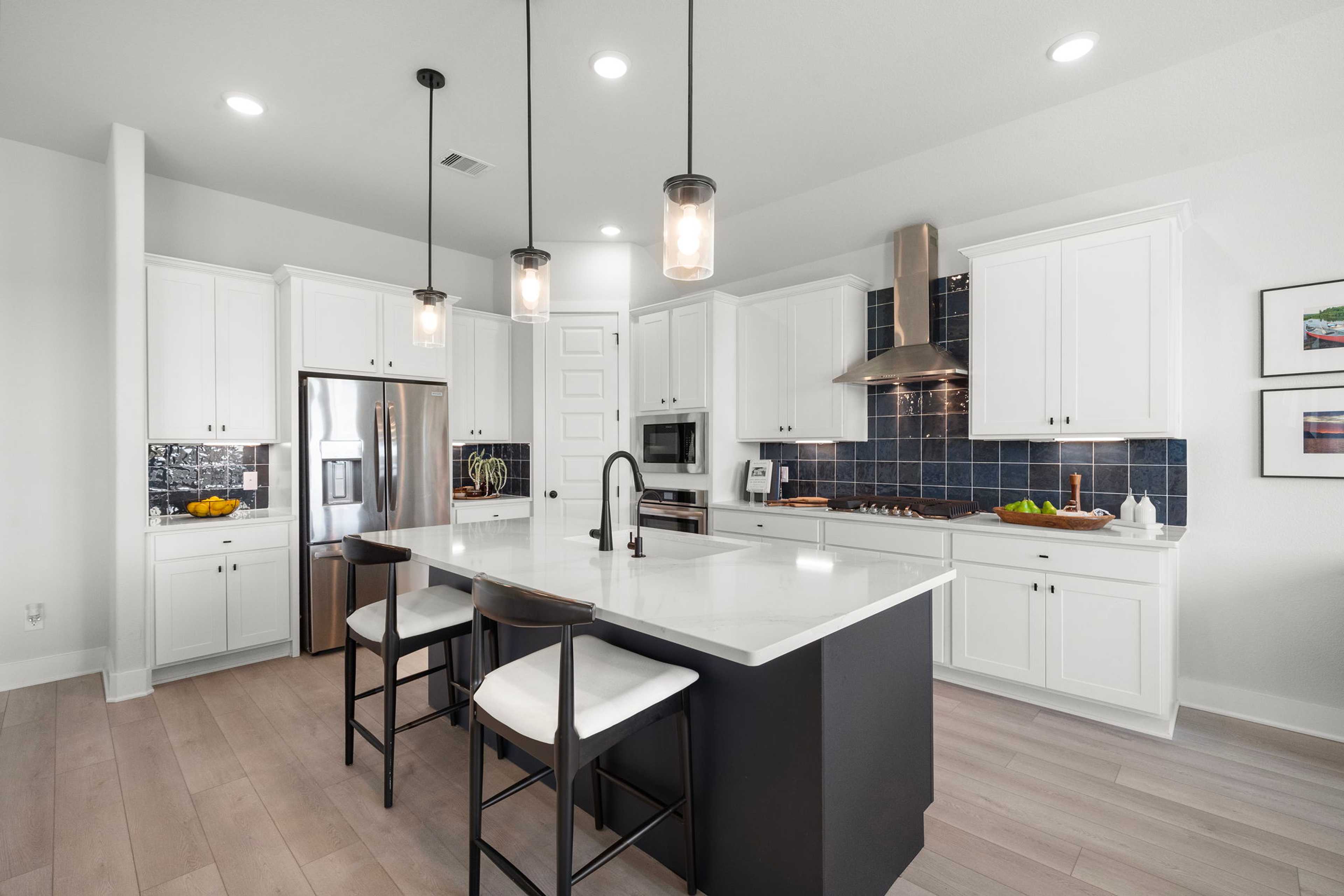 Modern white kitchen with island, blue backsplash, stainless appliances and hardwood floors at Lago Mar, Texas City TX