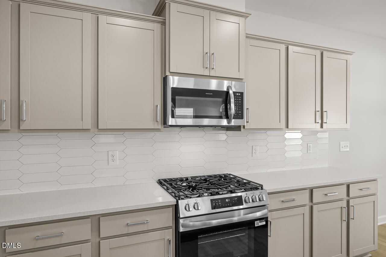 Modern kitchen with beige cabinets, white quartz countertops, and stainless steel appliances in The Gavin A, Lillington, NC.