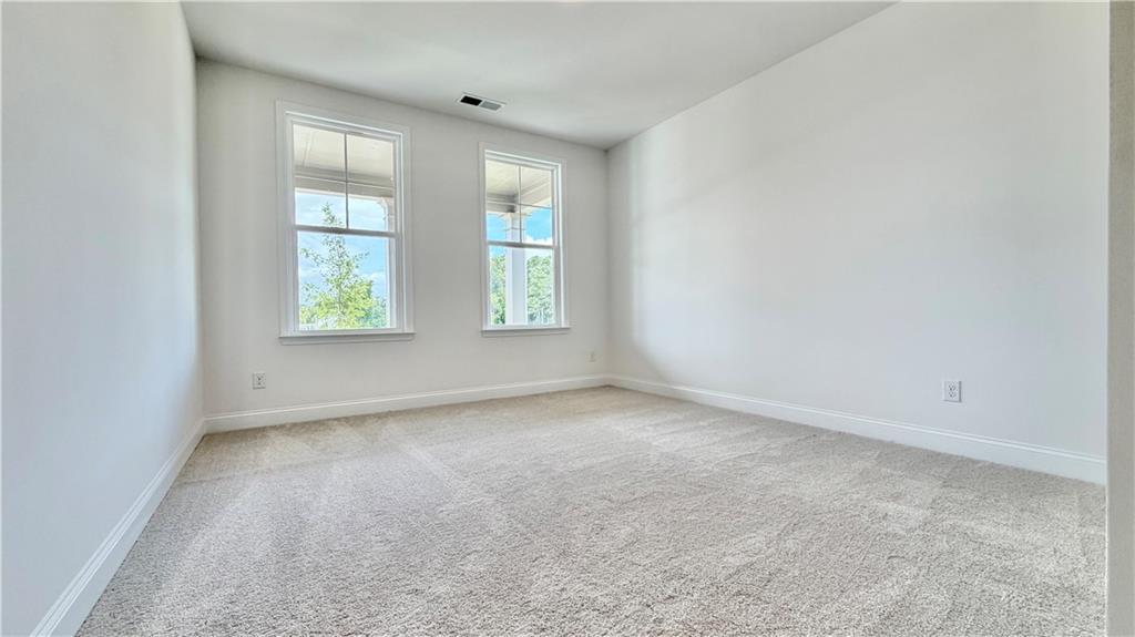 Bright, carpeted bedroom with large windows in The Hickory C floor plan at Wehunt Meadows, Hoschton, Georgia.