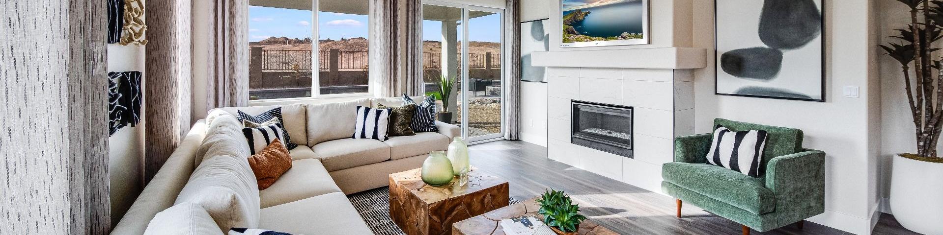 Spacious living room in South Ranch Western Collection, Prescott AZ with white sectional sofa, wood coffee table, fireplace, and large sliding doors