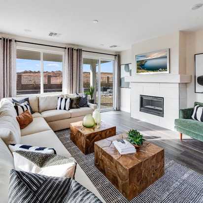 Spacious living room in South Ranch Western Collection, Prescott AZ with white sectional sofa, wood coffee table, fireplace, and large sliding doors