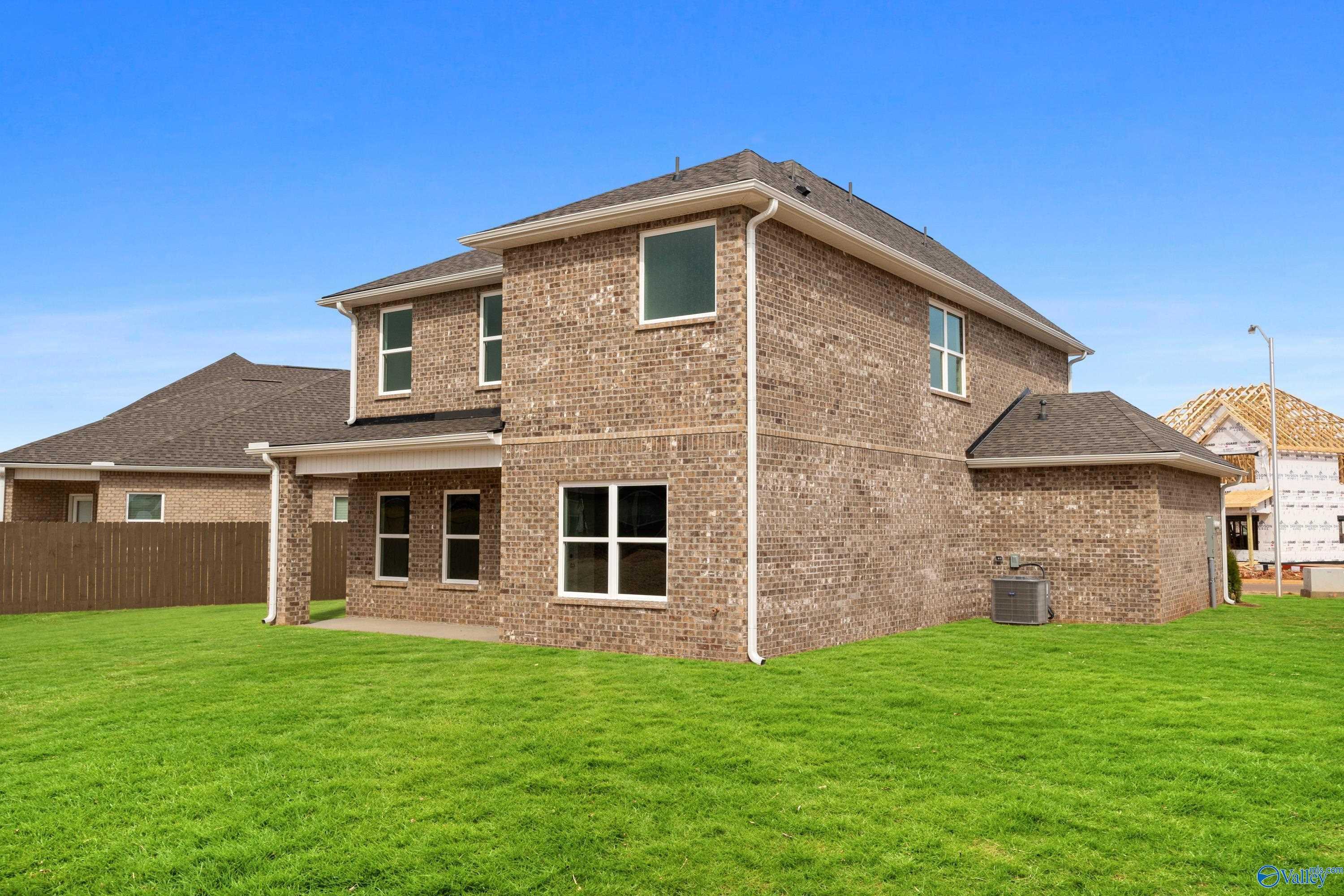 Two-story brick Aiken home by Davidson Homes with attached garage, covered patio, and lush green yard in Walker's Hill, Meridianville, Alabama