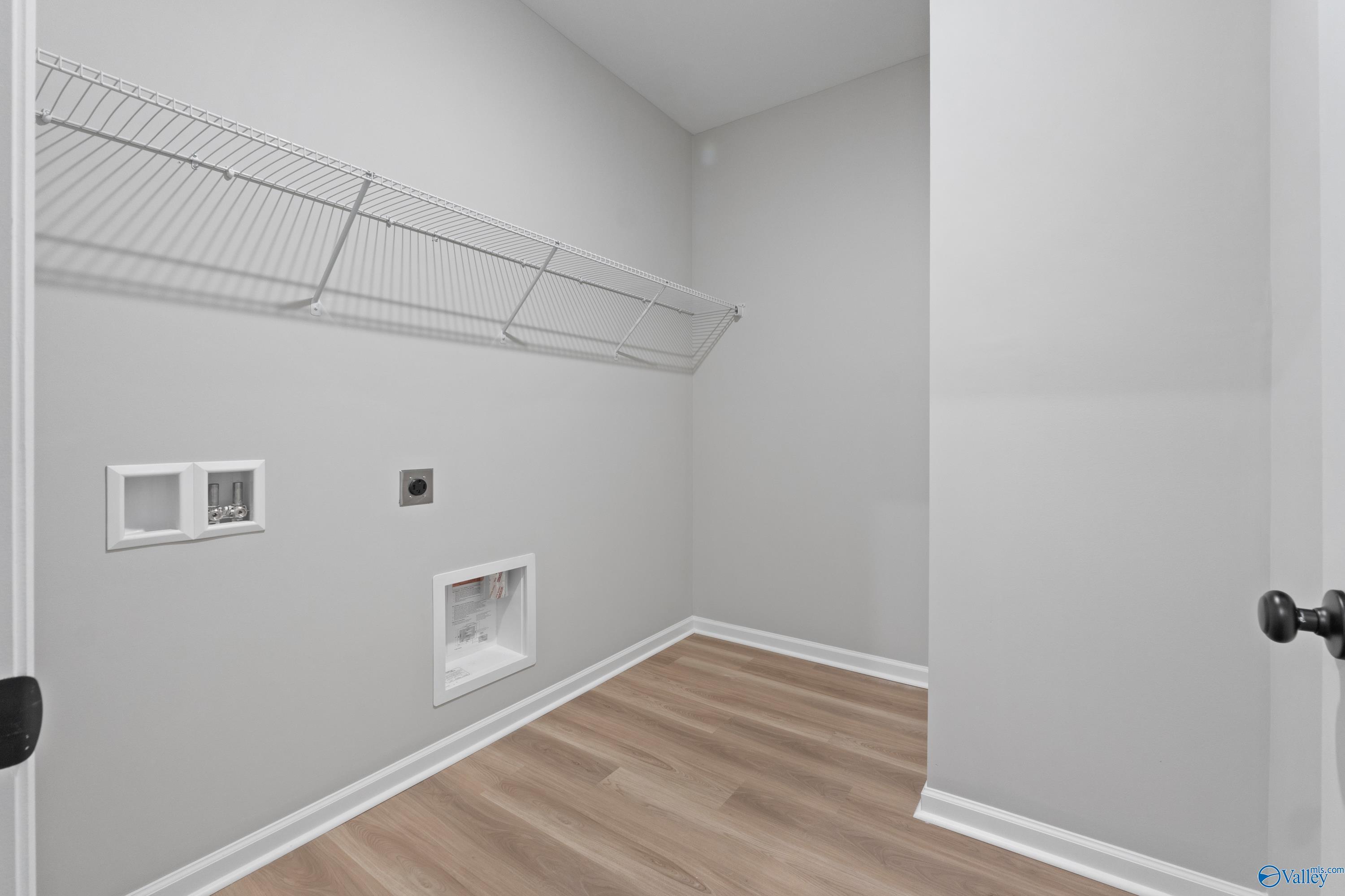 Spacious laundry room with wire shelving, washer-dryer hookups and hardwood floors in Davidson Homes The Phoenix, Hazel Green, Alabama