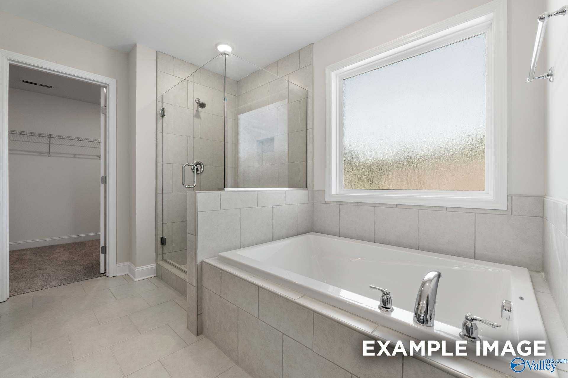 Luxurious master bathroom with freestanding soaking tub, glass shower and large window in Davidson Homes The Madison A, Meridianville, AL